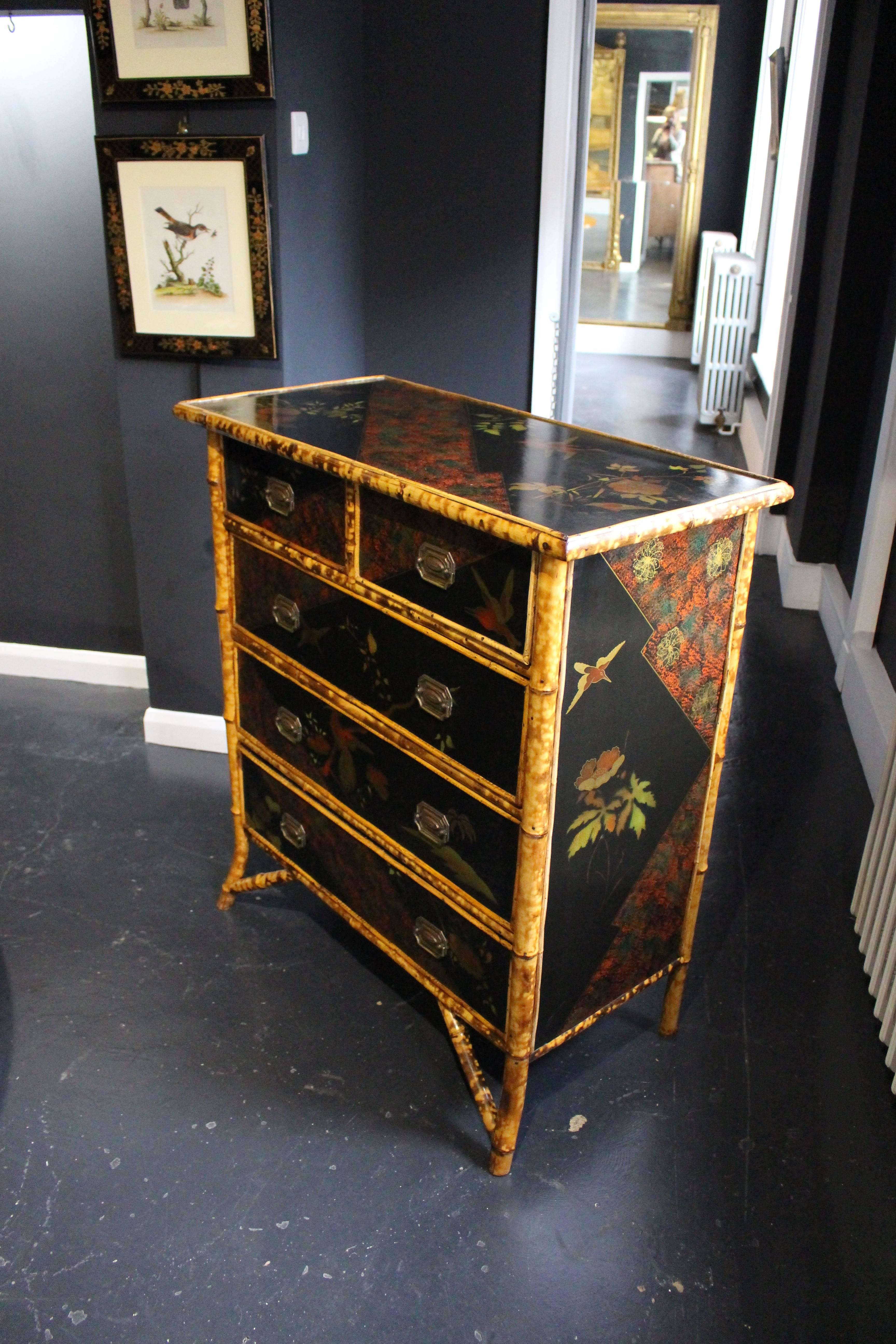 A Victorian black lacquer and japanned chest of drawers, circa 1890. With all-over bird and flowering branch decoration, two short drawers and three long drawers above out-swept legs. Frame made from bamboo.
