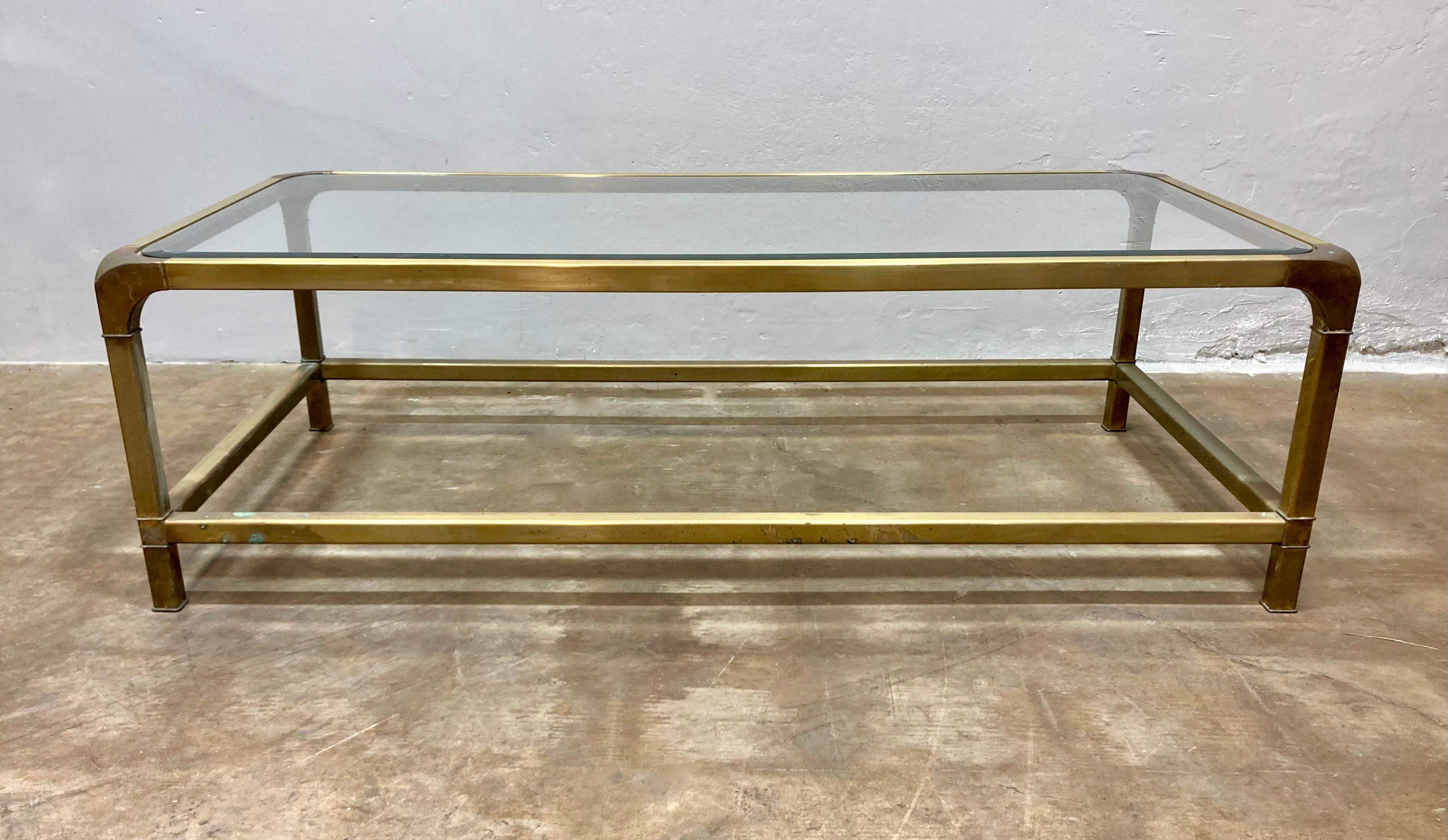 Magnifique table basse en laiton de Mastercraft. Fabriquée dans les années 1970 dans un style Mid-Century/Hollywood Regency, cette table est grande et pratique pour un usage quotidien. Les capuchons d'angle en cascade sont en aluminium et le verre a