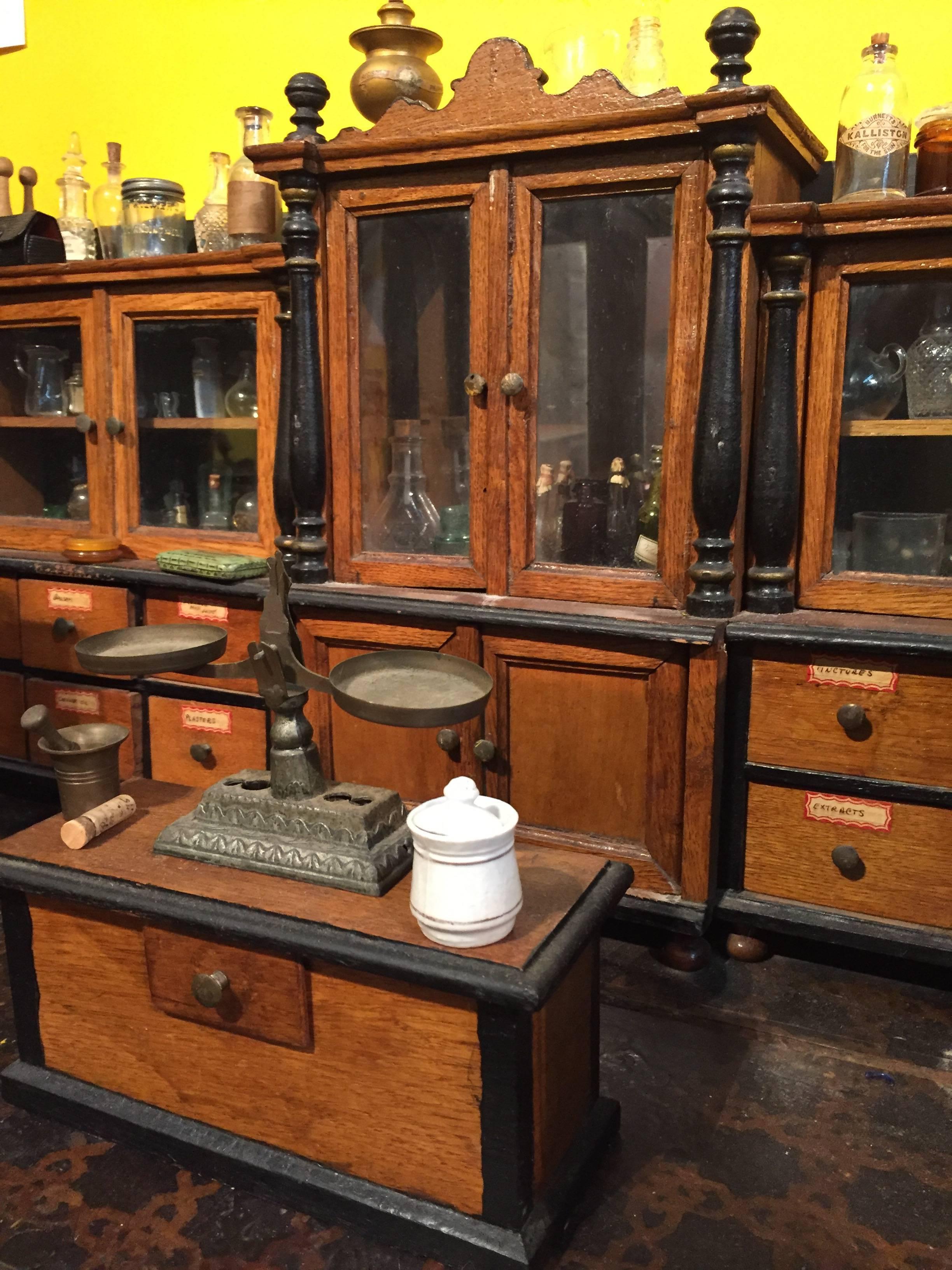 Probably made in Germany for the English market. Fully fitted with cabinets, counters, scales, bell, sign, bell, and accoutrements found in an apothecary shop of the day.