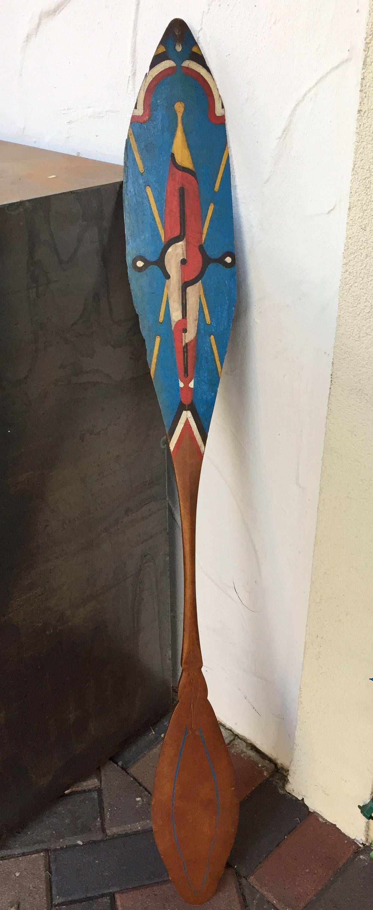 Finely painted with traditional geometric designs on both sides of one end, and subtle carved and incised flowing designs on both sides of the other end and adjoining shaft of the paddle. This example features an old used, worn patina and dates to