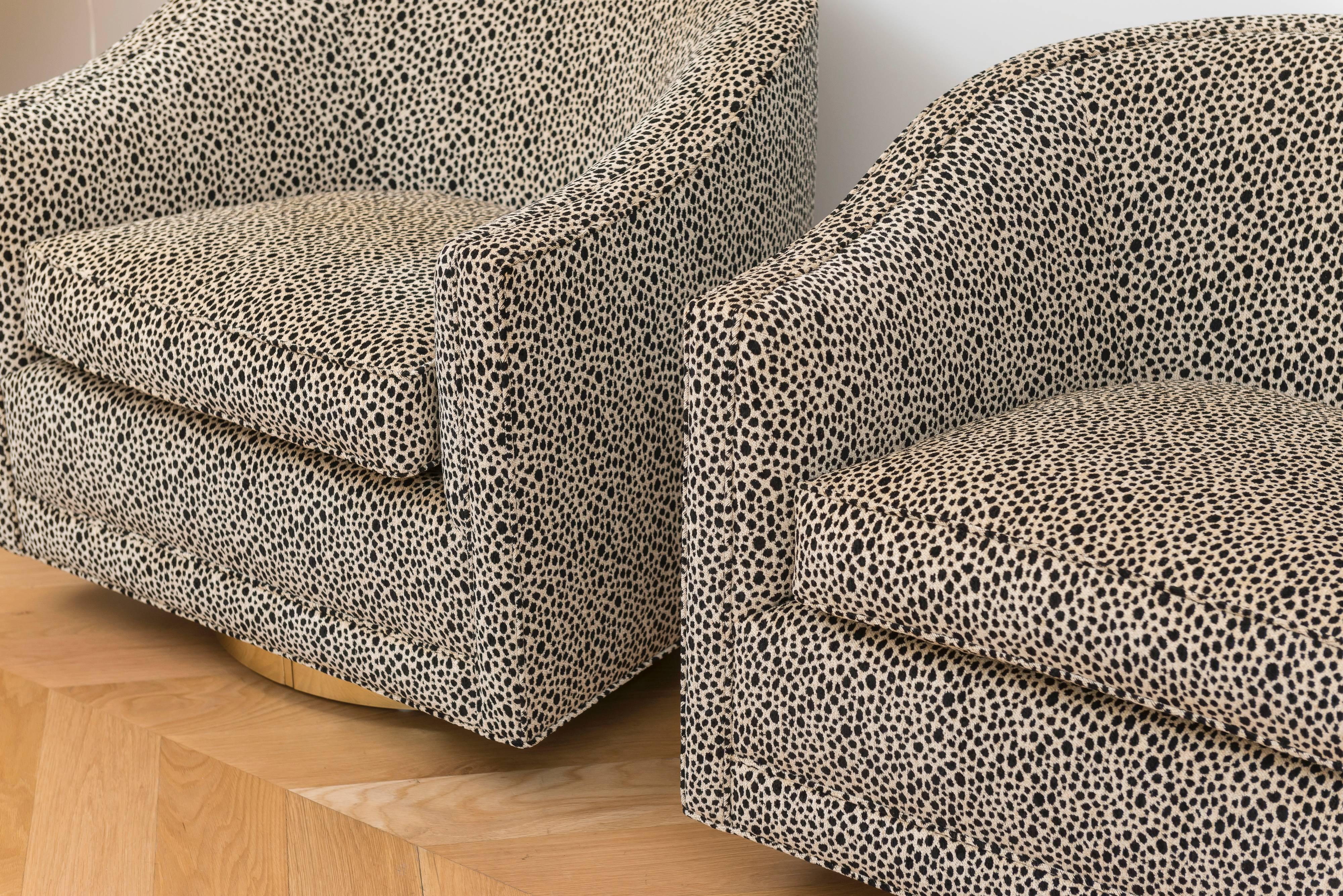 Great pair of Milo Baughman swivel armchairs with a brass plinth base, reupholstered in a faux black and white cheetah.