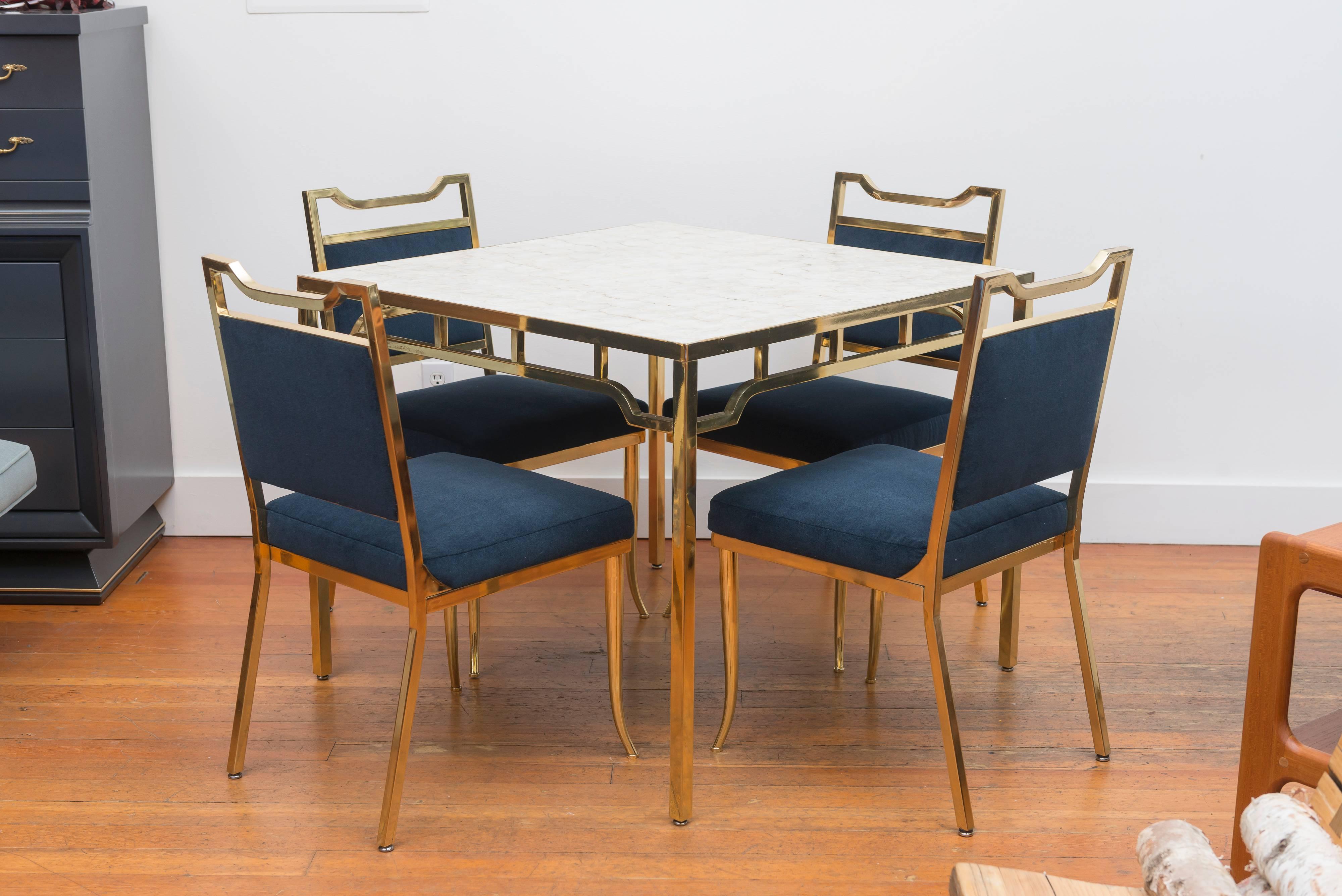 Willian Haines polished brass table set with capiz shell top with four chairs reupholstered in a blue Maharam wool.