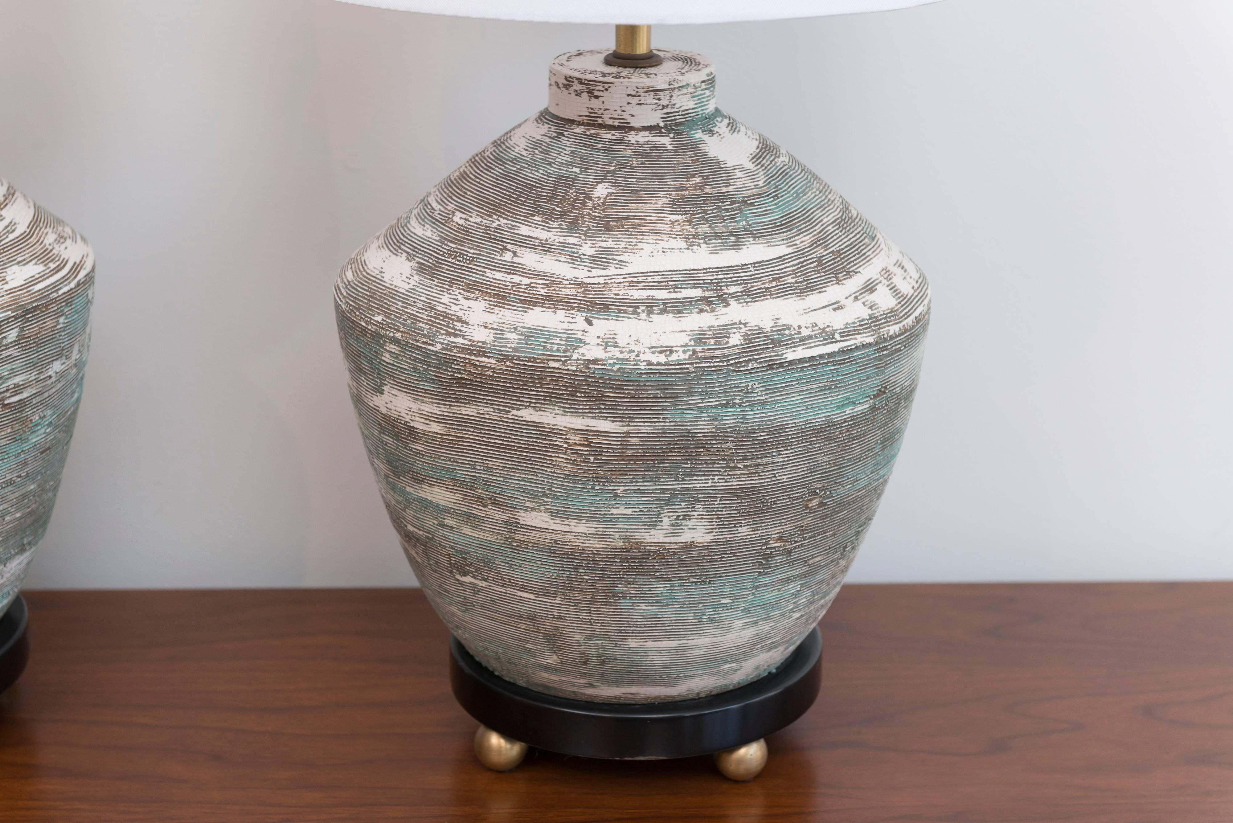 Textural ceramic lamps with brass ball feet.