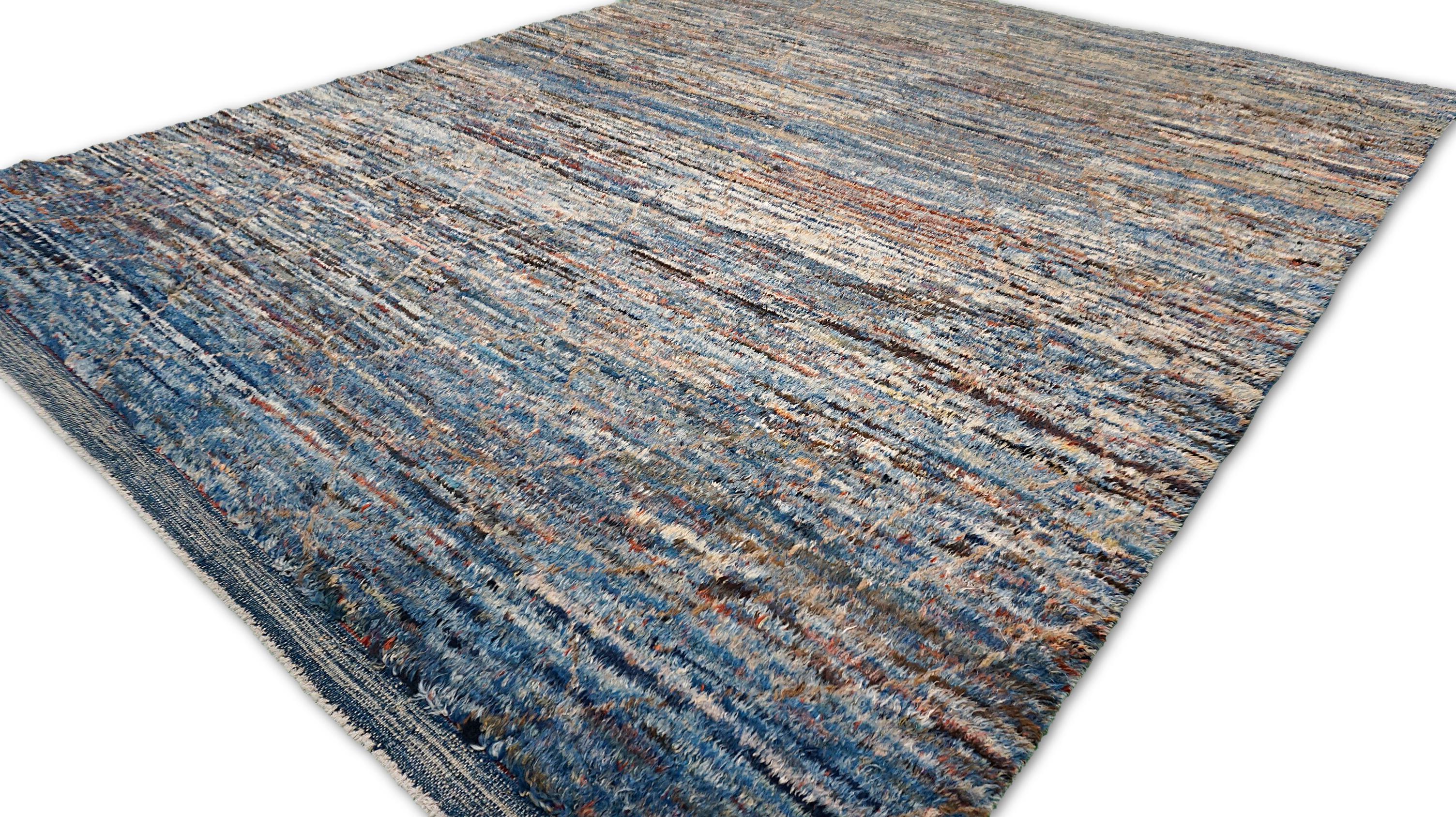 Questo straordinario tappeto in lana annodato a mano presenta un'accattivante miscela di toni indaco, blu, arancione, avorio e marrone, creando un pezzo ricco di texture che aggiunge profondità e carattere a qualsiasi interno. Il suo design astratto