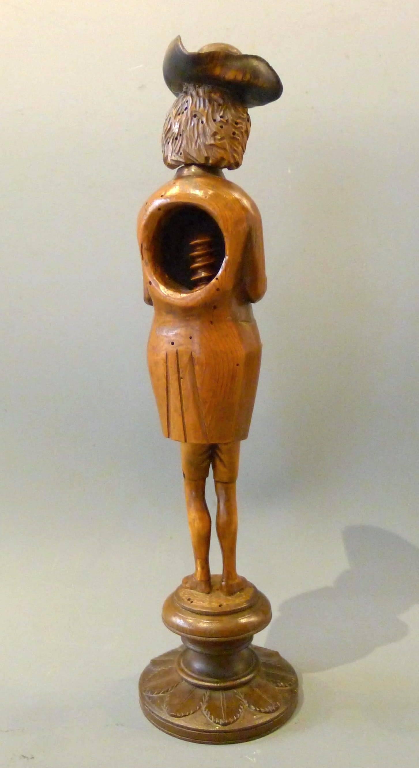 Nutcracker with cage, representing a fine and smiling character, dressed in a fitted coat, combed by a three-cornered hat, hands put on the stomach. 
Legs are extended by a binding screw. 
Circular base decorated with foliages. 
