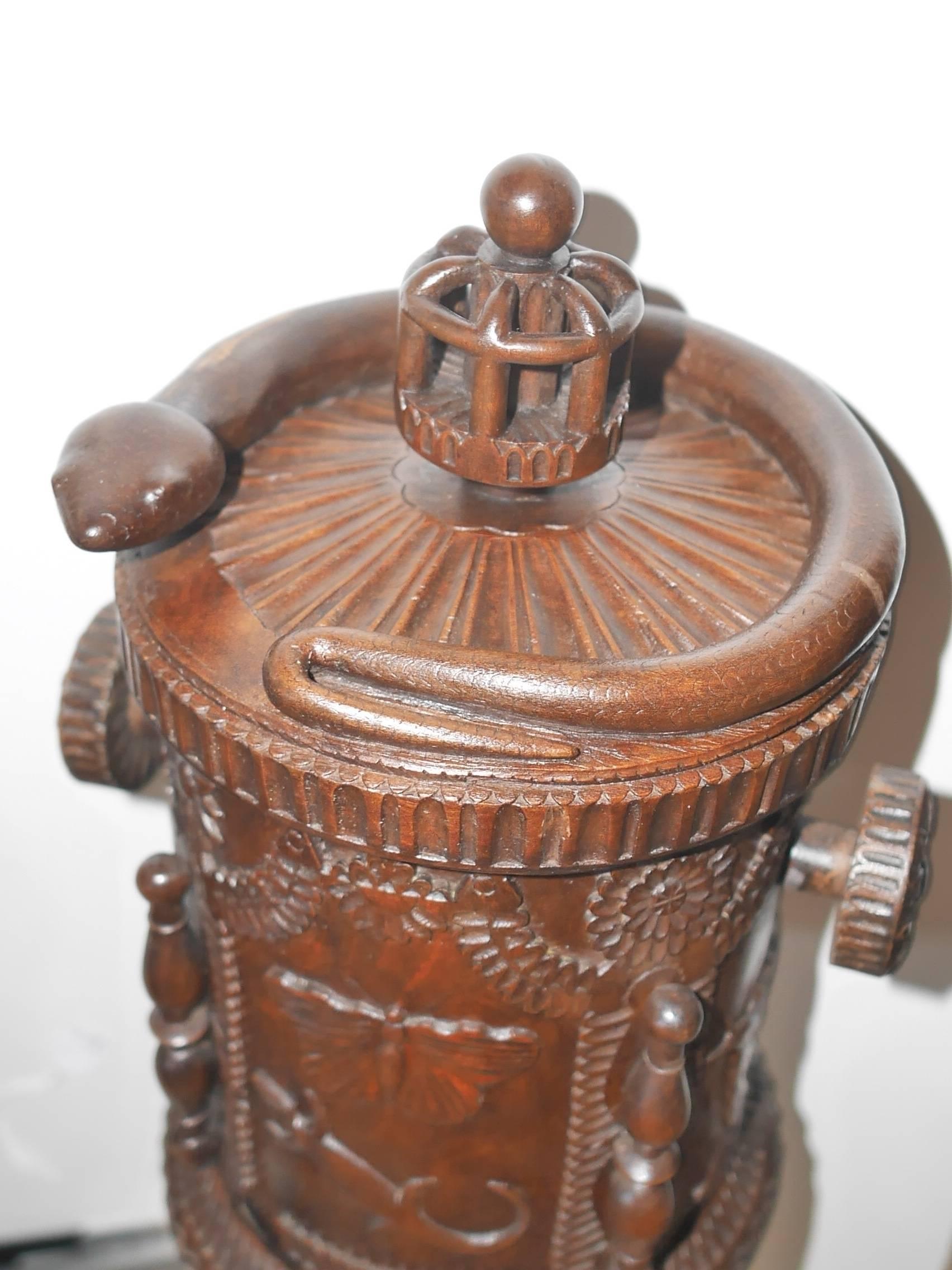 This wooden tobacco box beautifully carved with lizards, fishes, butterflies, wine leaves and grapes and various flowers. There are four little turned pillars incrusted all around and a delicate engraving work on the plinth and on the lid the latter