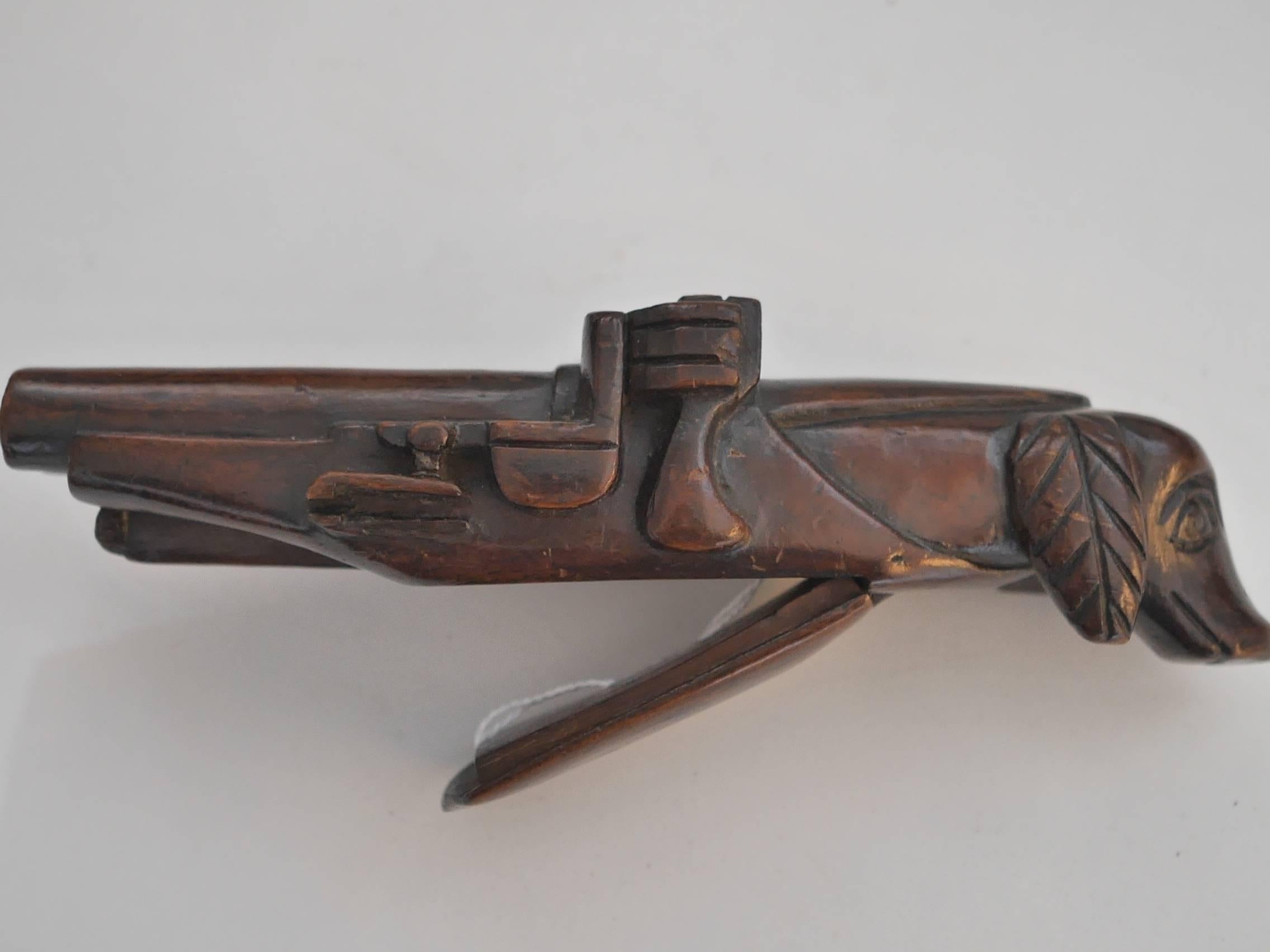 Mahogany wood carved snuffbox featuring a retriever on one side and a gun barrel on the other. 
The tobacco was placed on the little box underneath.

This object belonged to the 