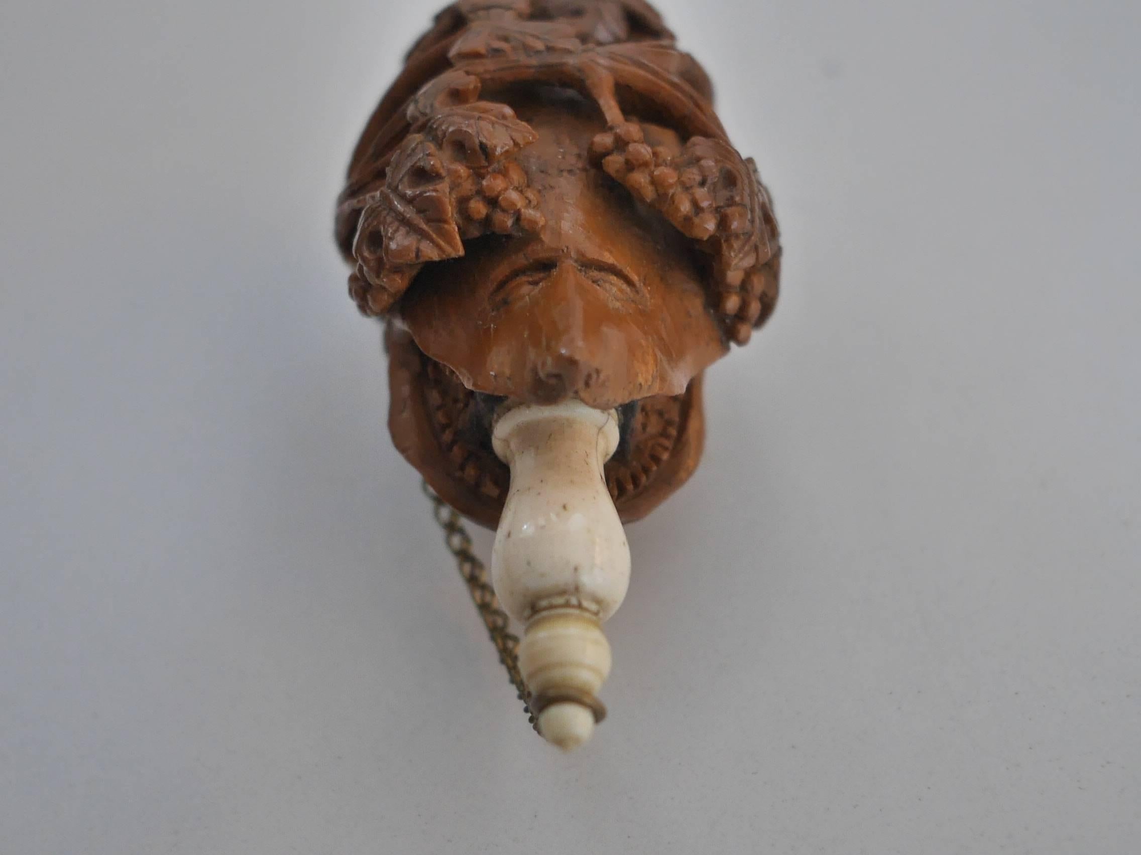 Very interesting work of carving on this Tagua Nut*** Snuffbox. Deeply hollowed details of vine leaves and grapes. One side features a dog or a wolf head holding the bone closing tip in its mouth; the other side, on the contrary, is decorated by a