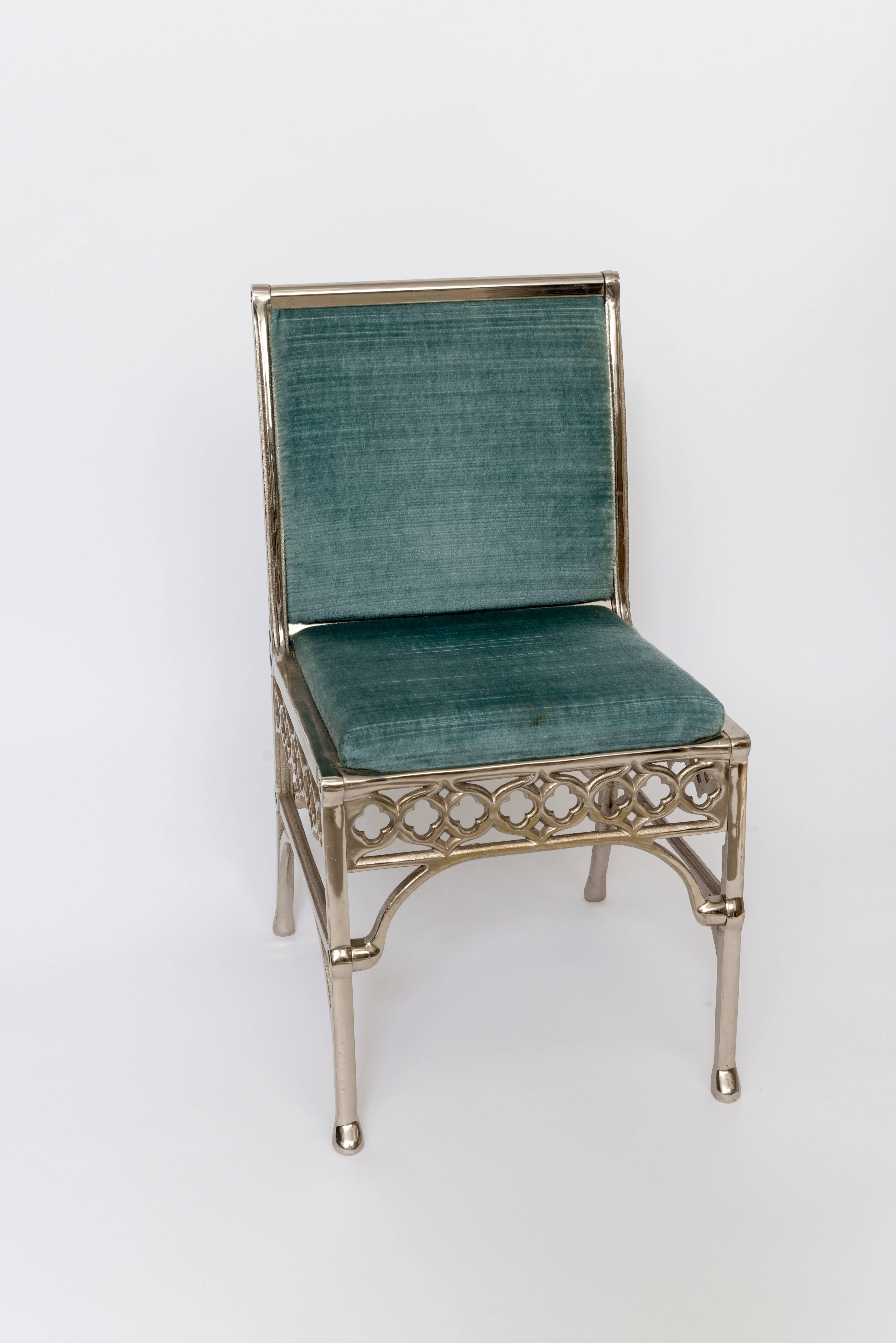 A unique set of eight [8] Neo-Gothic dining room chairs that reflect a Hollywood Regency feel as well. Upholstered in a teal blue shade of velvet in excellent condition. These chairs are quite solid and beautifully designed. Table shown with marble