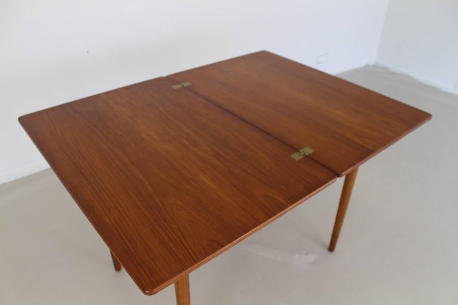 Excellent Danish design by Hans Wegner
The small kitchen dinner table has a unfoldable leaf.
During the unfold the tabletop is pivotted around so a larger table presents itself. A larger storage space is under the tabletop.
Top in teak and frame