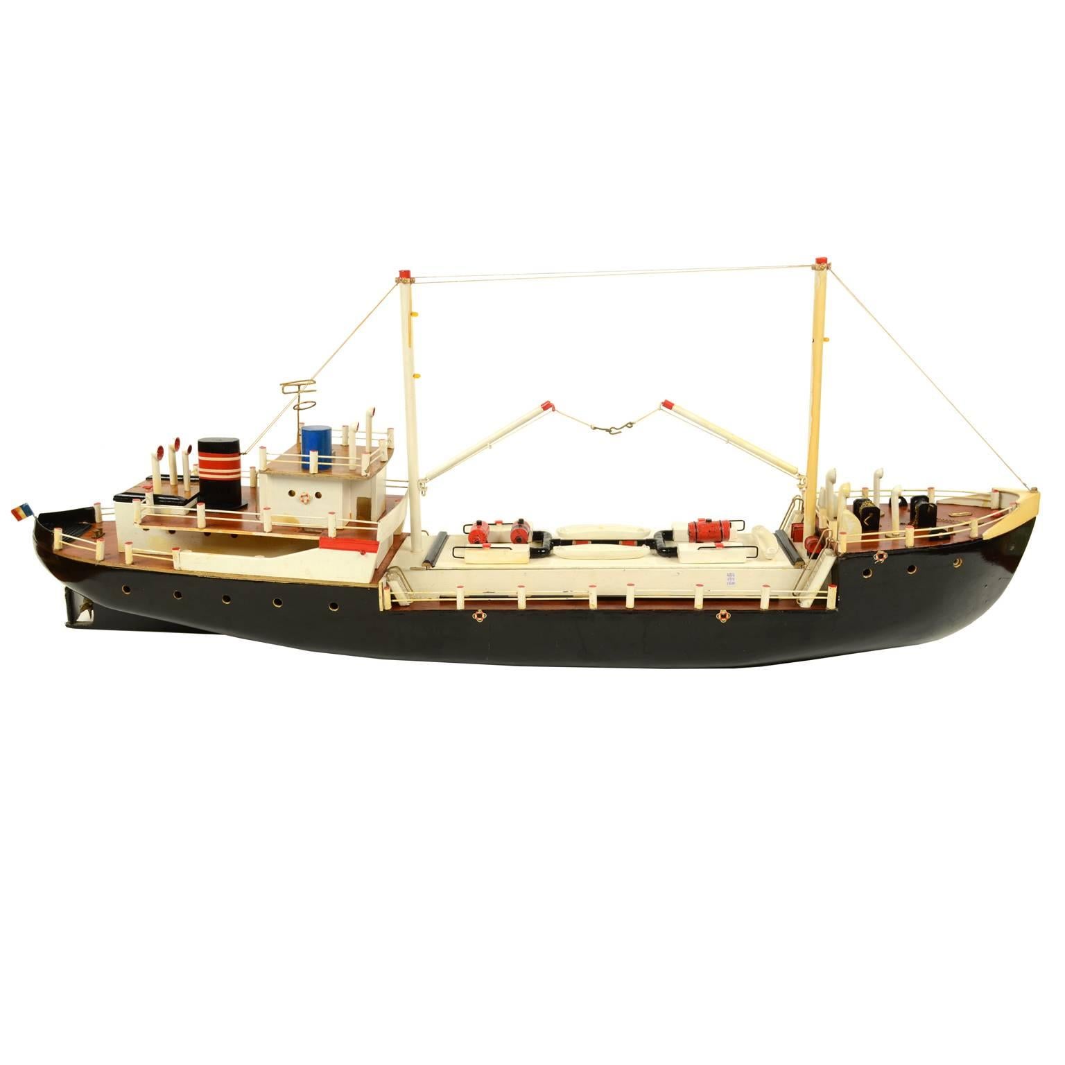 Scale model of a 1,000-ton boat depicting a small freighter used for the coastal cabotage. French flag, two derricks for loading and unloading cargo, central winch on the bow and smokestack on the stern. Made in 1950s. The model is made of wood,
