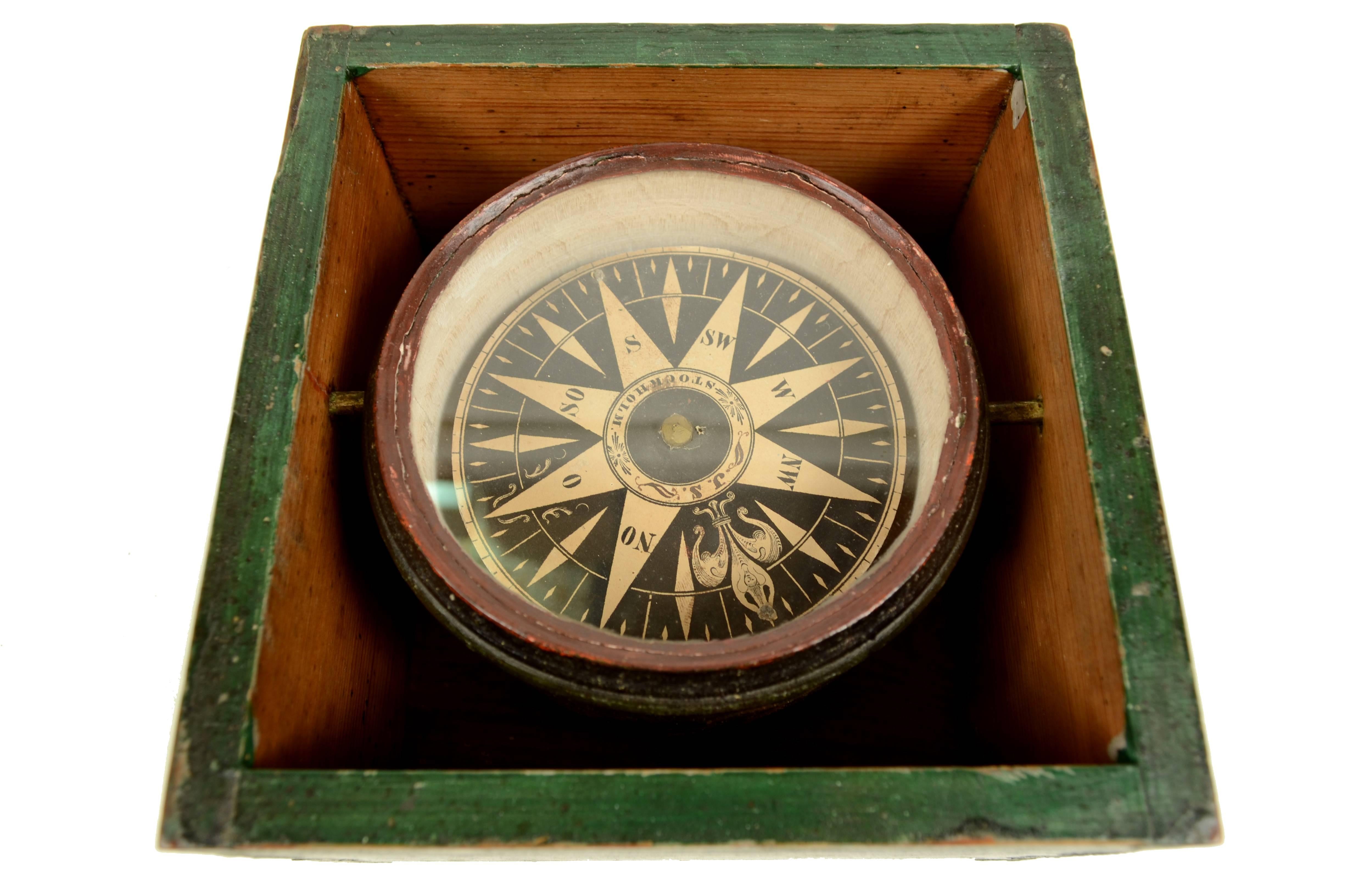 Dry magnetic compass placed in its original wooden case green painted, compass card with eight winds on paper, signed J. S. Stockholm made in the early 19th century. The compass has a cylindrical container of brass, on the bottom of which it is
