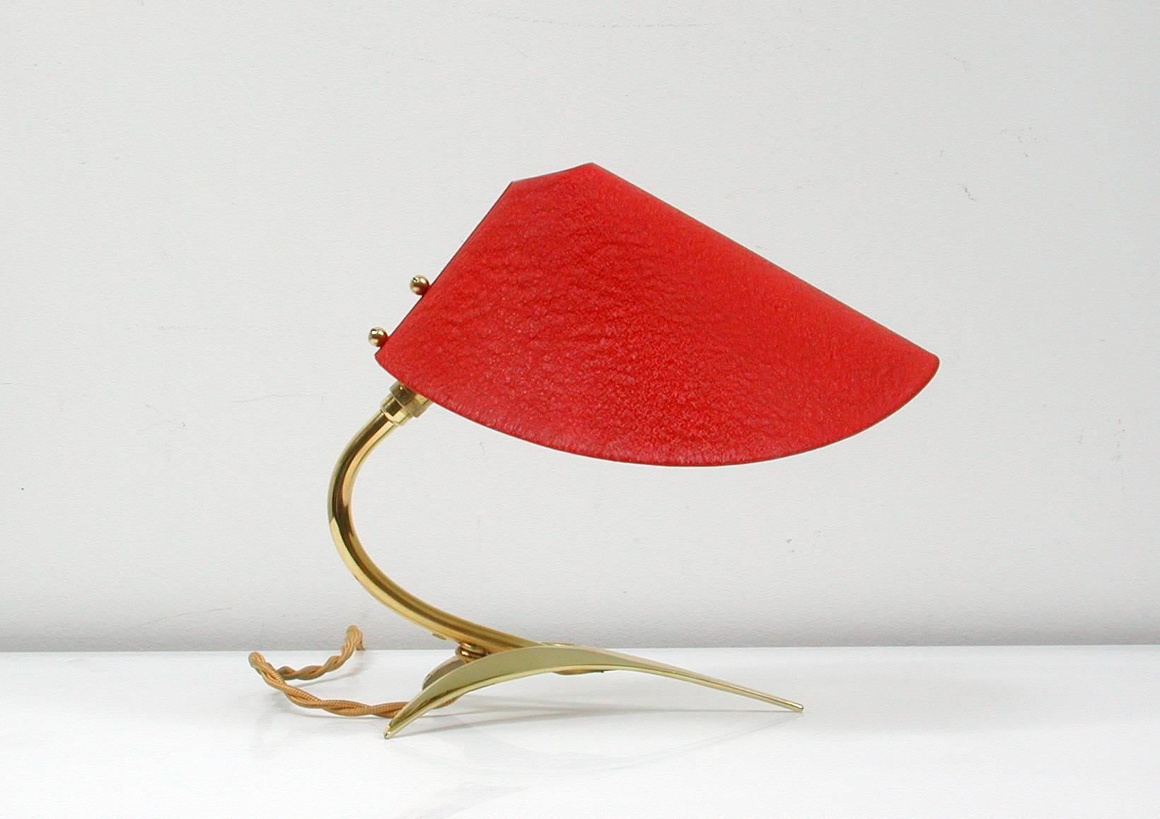 Mid-Century brass and red lacquered table lamp, made in Austria in the 1950s in the manner of JT Kalmar.
The lamp has got a tripod brass base and an adjustable red lacquered lamp shade. It has been rewired with new fabric wiring and will work on