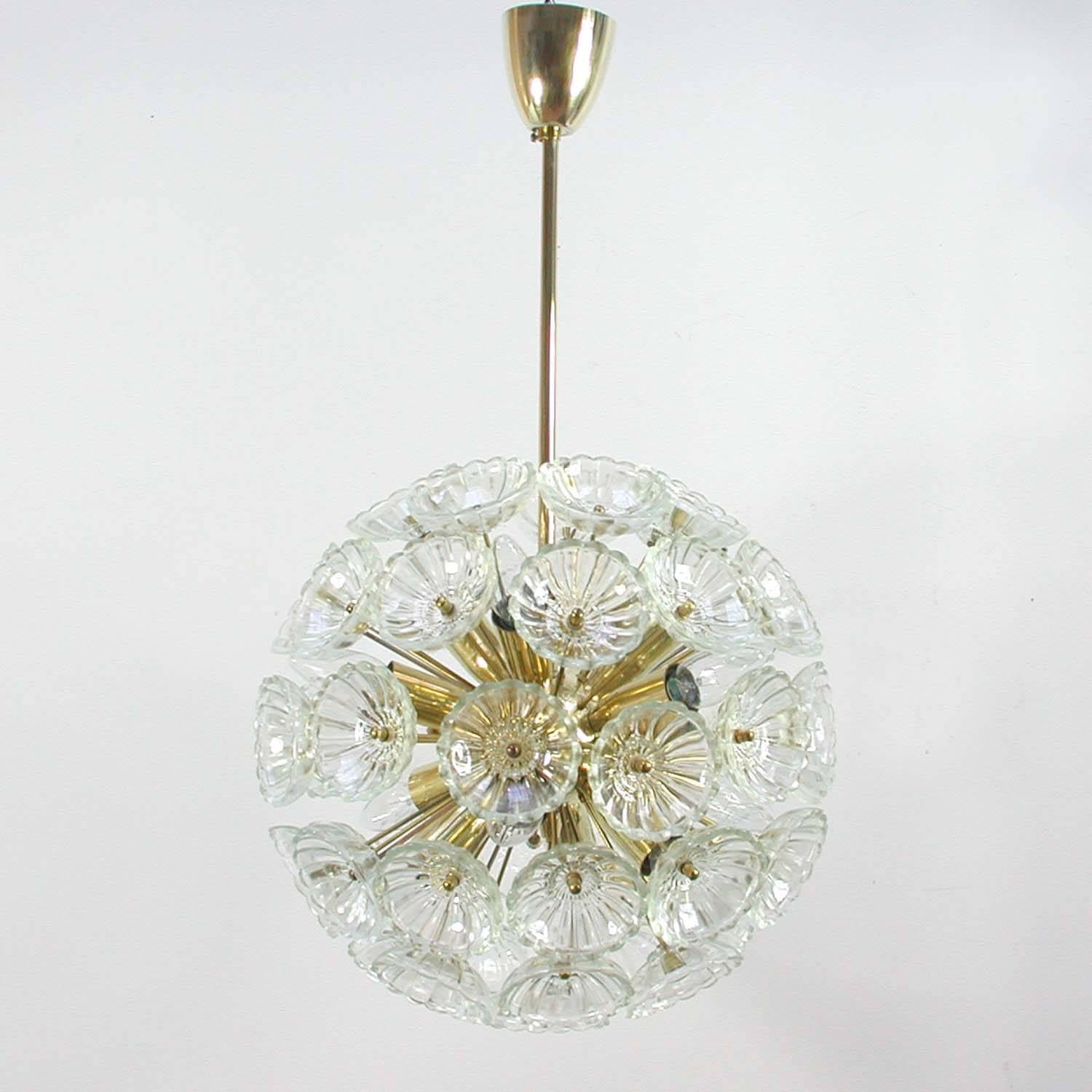 Impressionante lampadario a dente di leone in vetro e ottone, realizzato in Germania negli anni '60. Il lampadario ha dodici luci e 52 fiori di vetro.
Ottone lucidato ma ancora con una bella patina calda.