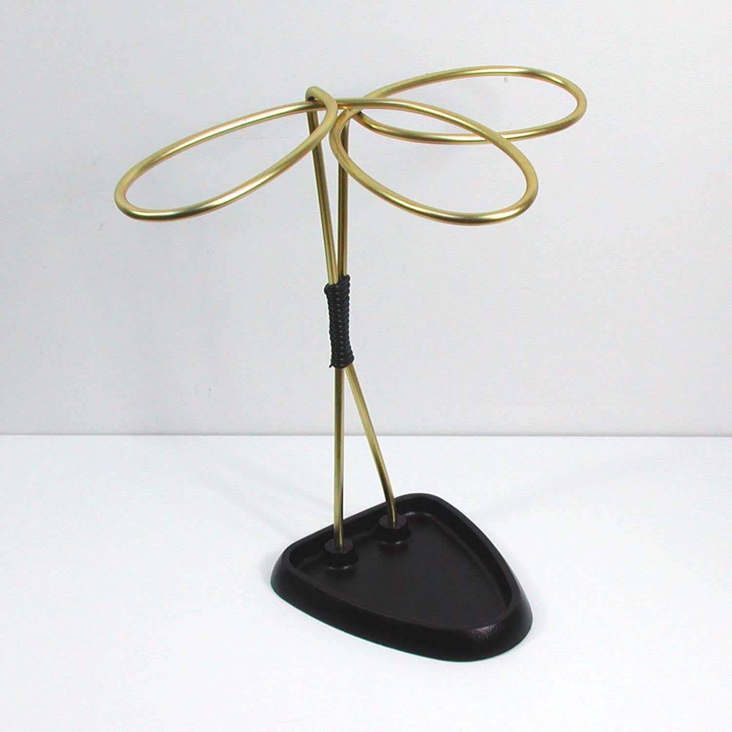 This midcentury umbrella stand was made in Austria in the 1950s.
It is made of gold anodized metal and has got a black lacquered cast iron base.