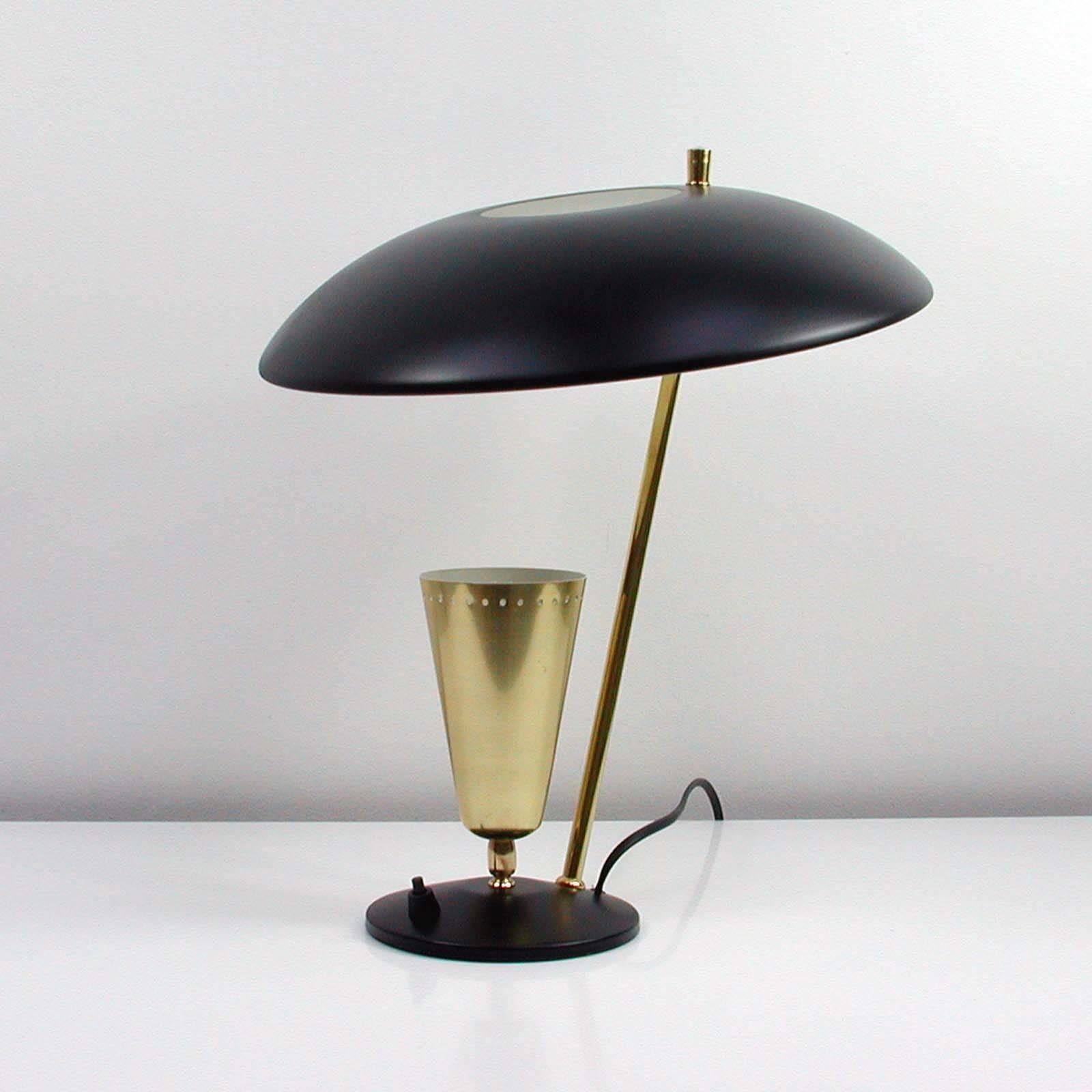 This vintage reflecting midcentury table lamp was produced in France in the 1950s and manufactured by Aluminor, nice.

The lamp has got an adjustable black lacquered reflecting top lampshade and an adjustable conical brass lampshade on the base.