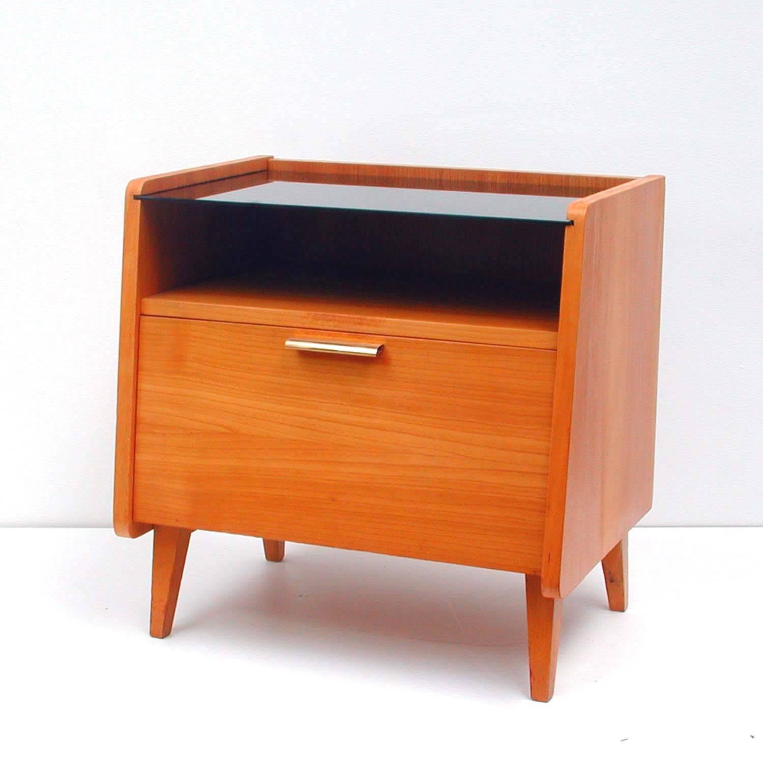 This vintage midcentury chest or commode was manufactured in Germany, during the Scandinavian modern period. It is made of teak and has got a black glass top.