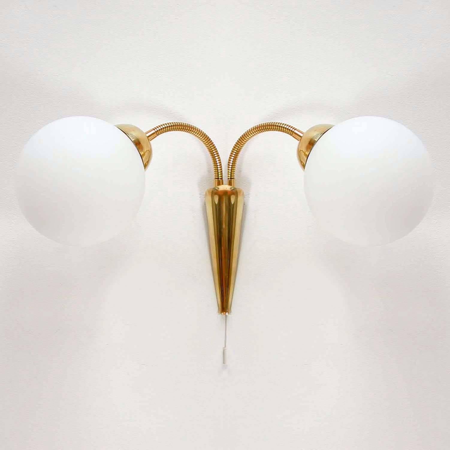 This vintage wall light was manufactured in Italy, in the late 1950s.
It has got double-gooseneck brass lamp arms and white opal glass lampshades.
The sconce has been rewired and is suitable for use in any country of the world.