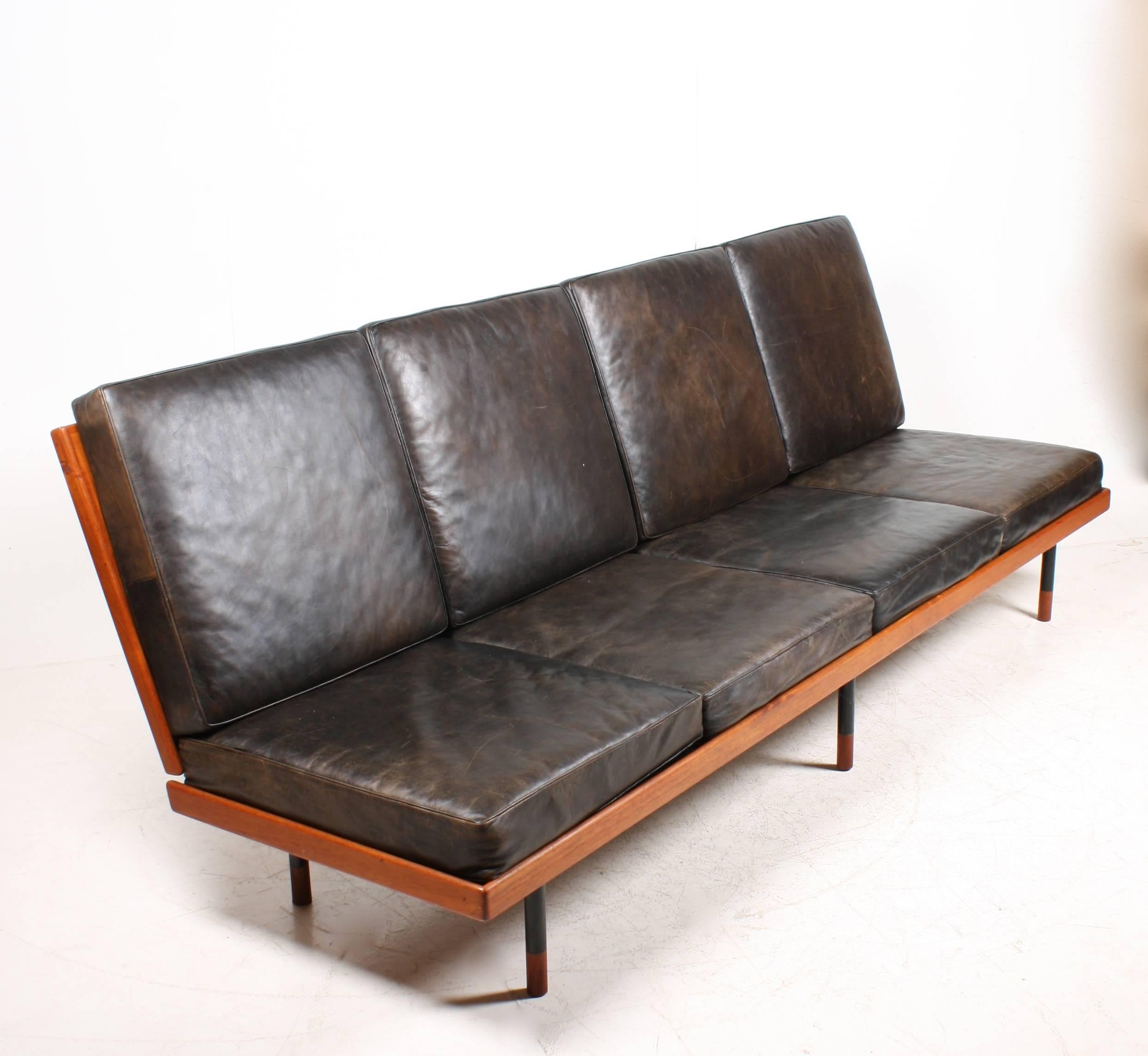 Elegant sofa with a frame of teak on metal legs. Patinated leather seat and back. Designed in the manner of the Danish designer Finn Juhl - Made Denmark in the 1950s. Great original condition.