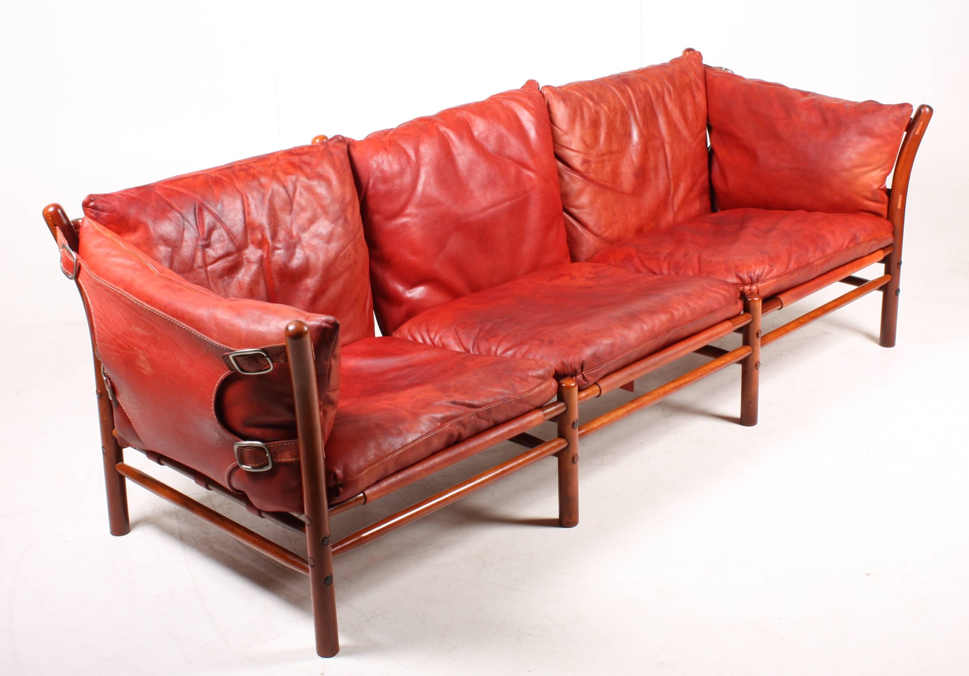 Three-seat sofa in beautiful patinated red leather, wood frame and brass hardware. Model Ilona designed by Swedish architect Arne Norell for Norell Möbel AB in the 1960s. Great original condition.