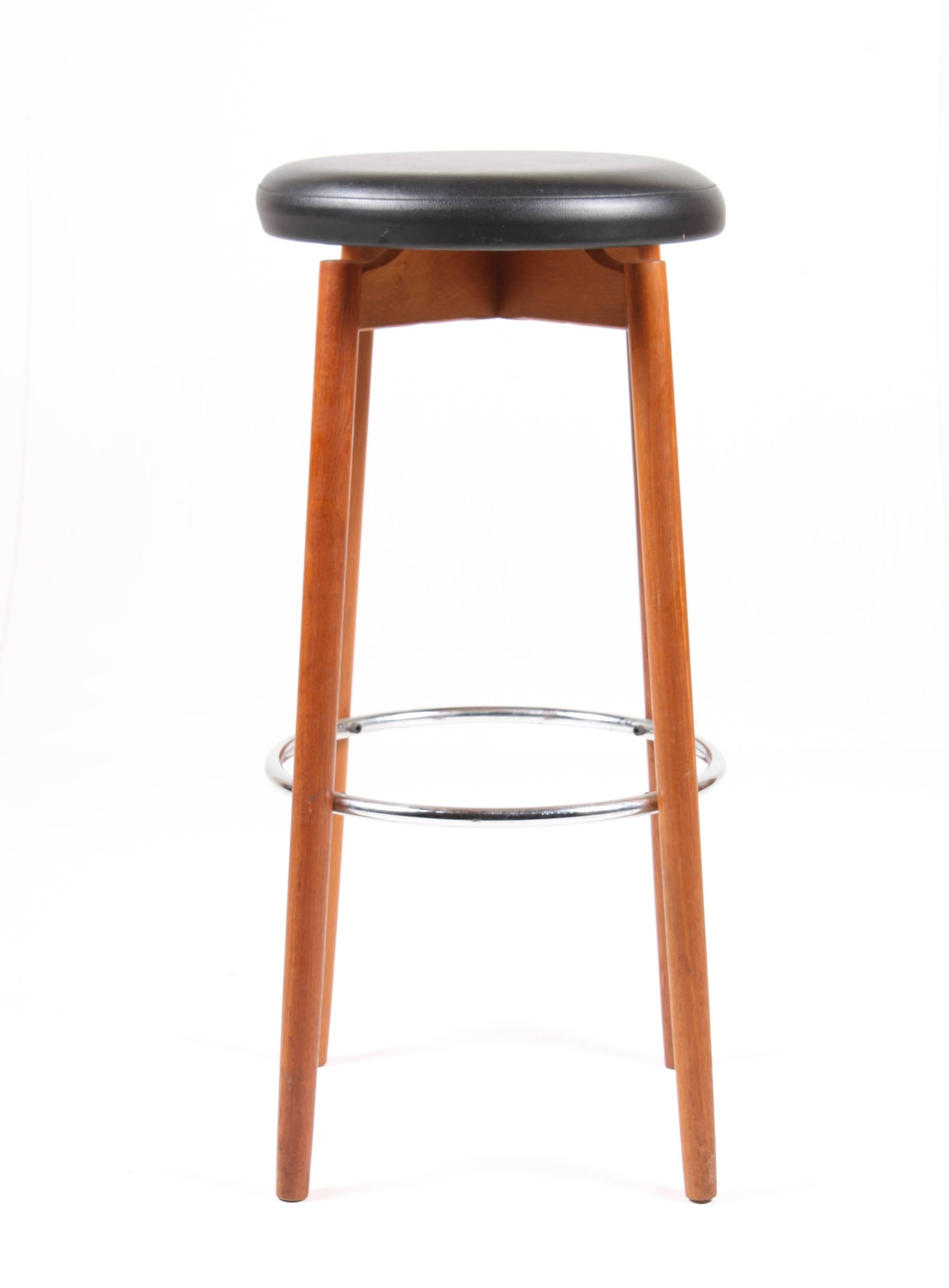 Set of three great looking high stools in solid teak with a chromed metal footrest and black vinyl seats. Perfect for a bar or in the kitchen. Made in Denmark in the1960s. Great condition.