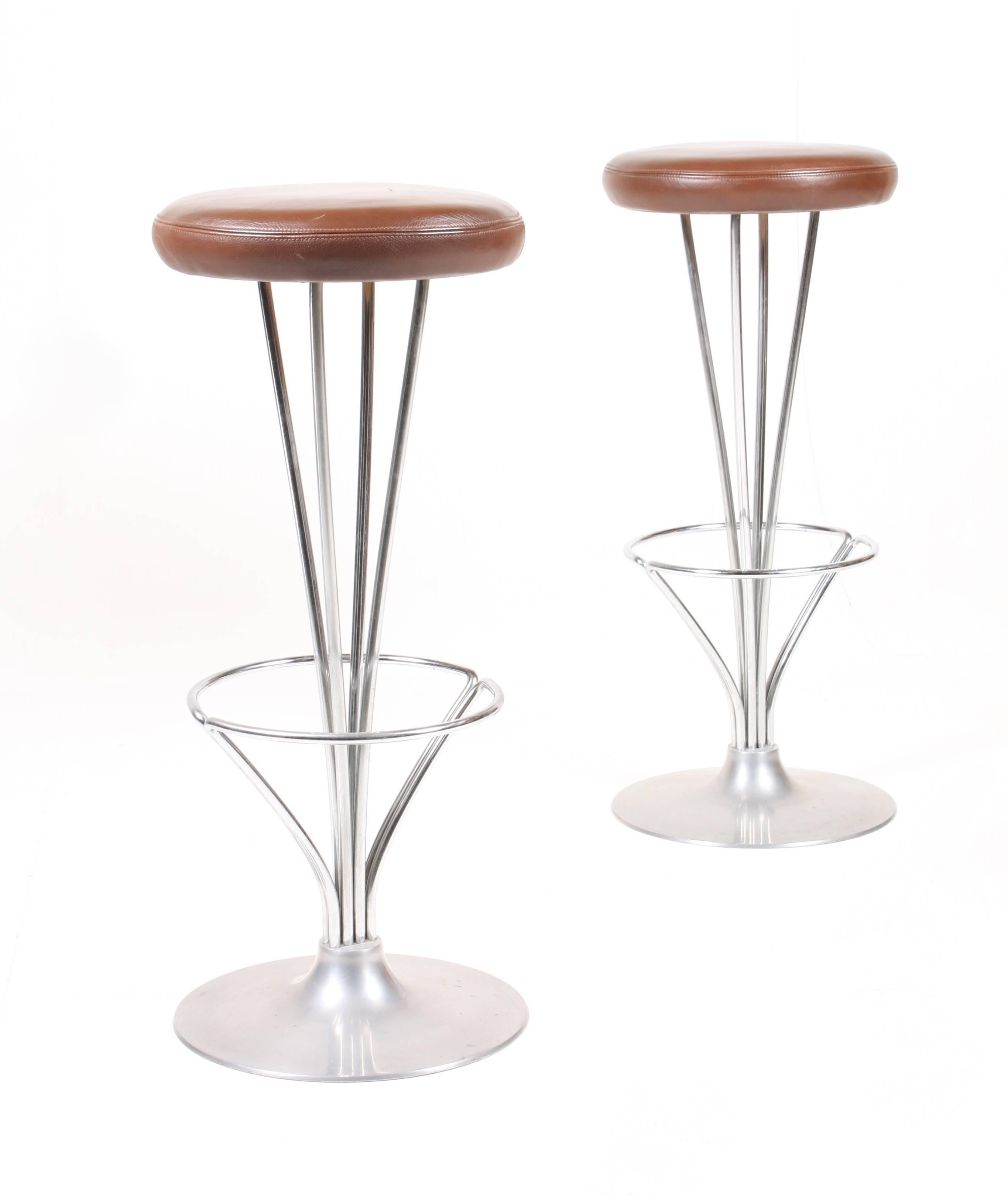 Pair of high stools in metal with patinated leather seats. Designed by Piet Hein for Fritz Hansen. Made in Denmark, great original condition. Ideal for the kitchen or in a bar.