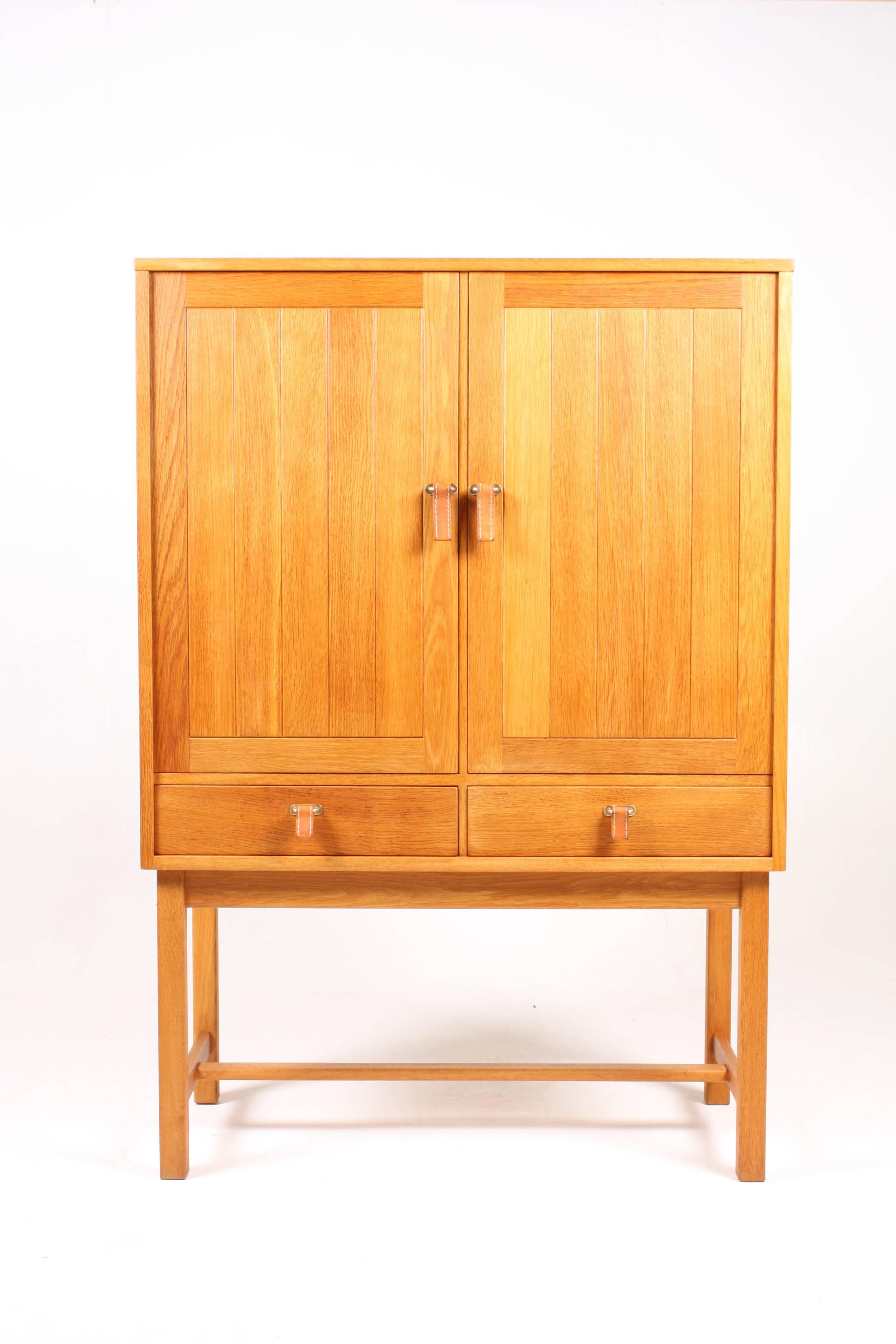 Pair of stunning cabinets in solid waxed oak, hard ware in brass and patinated leather handles. Nice and useful interior with drawers and shelves. Designed by MAA Kurt Ostervig for K.P. furniture in the 1960s. Great original condition.