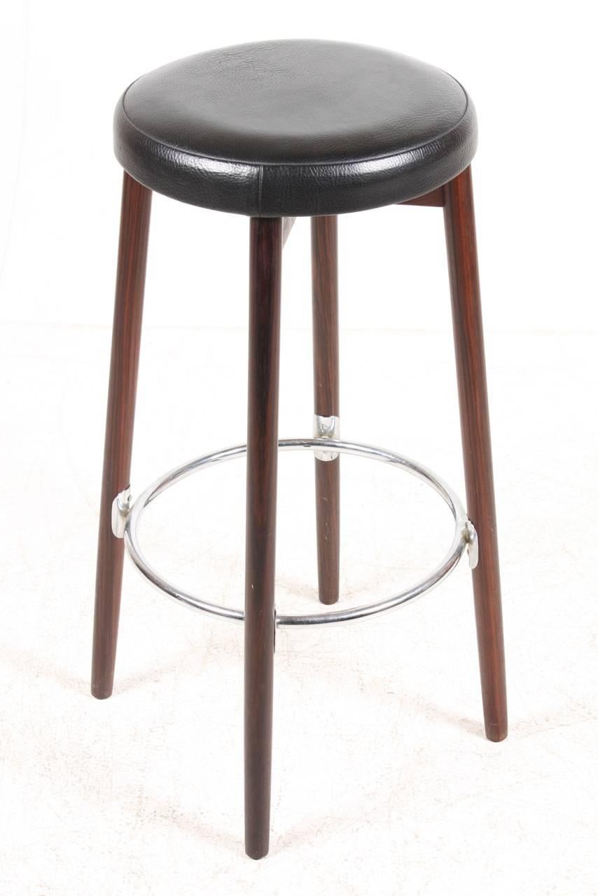 This set of three bar stools with solid rosewood frame and black Naugahyde seats. Made in Denmark in the 1960s.