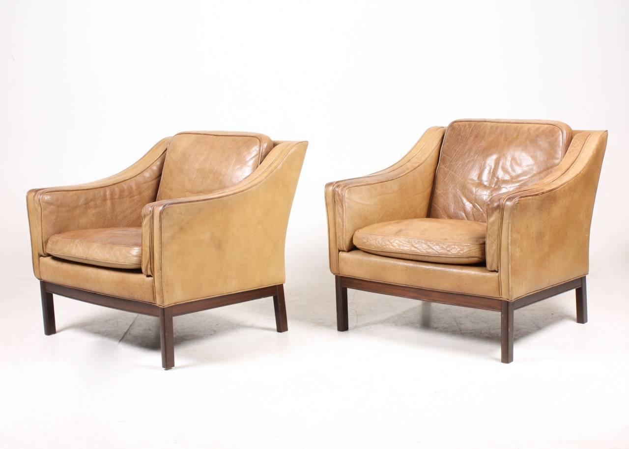 Great looking pair of lounge chairs in patinated leather on a solid wood base designed by Grant design studio in the 1970s. Original condition.