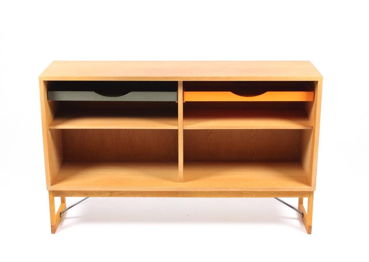 Low bookcase in oak with adjustable shelves and colored drawers. Designed by Danish architect Børge Mogensen for Karl Andersson cabinetmakers. Made in Sweden in the 1960s. Great original condition.