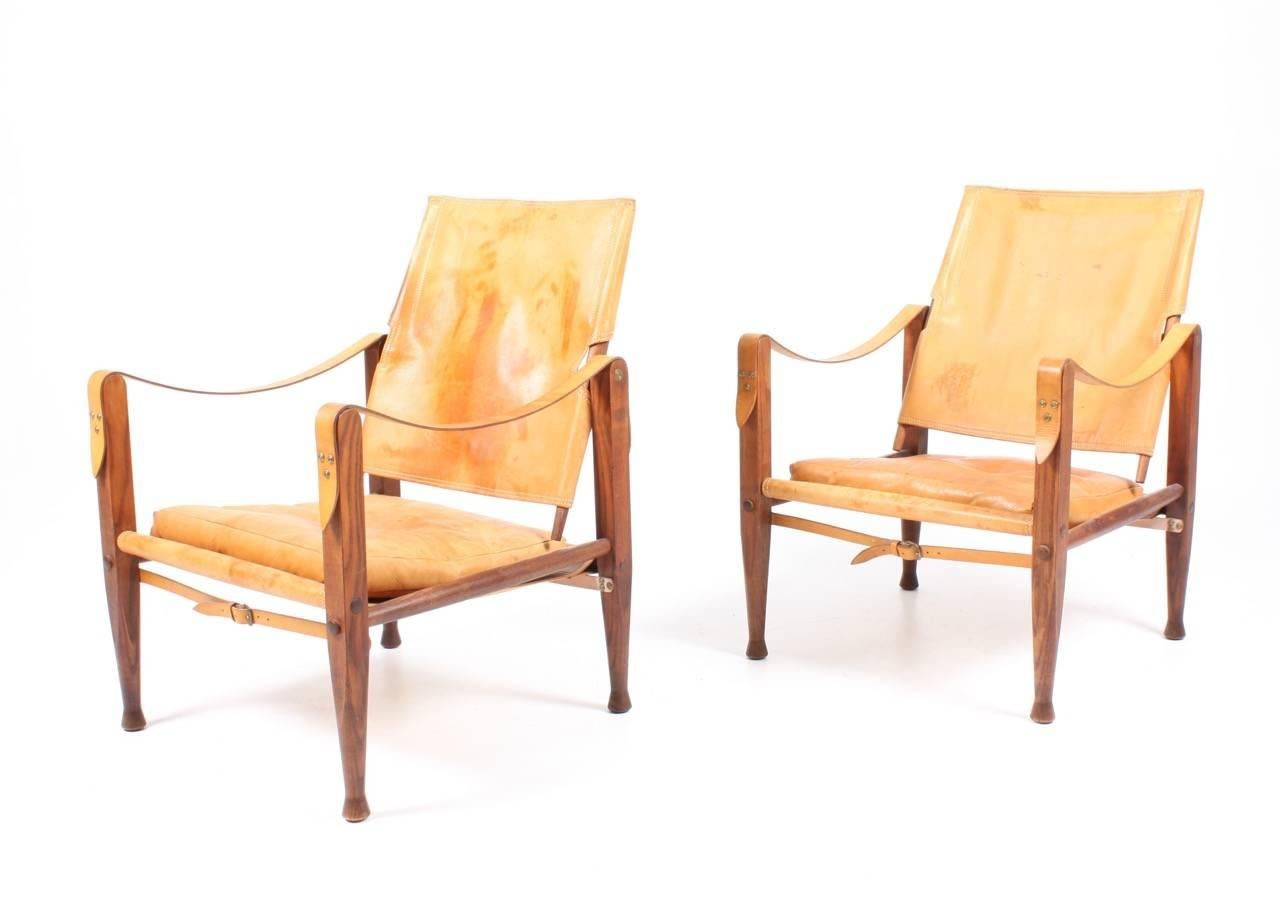 Pair of safari chairs in elm and well patinated naturel leather designed by Maa. Kaare Klint for Rud Rasmussen cabinetmakers in 1933. This pair is from the 1960s. Made in Denmark. Great original condition.