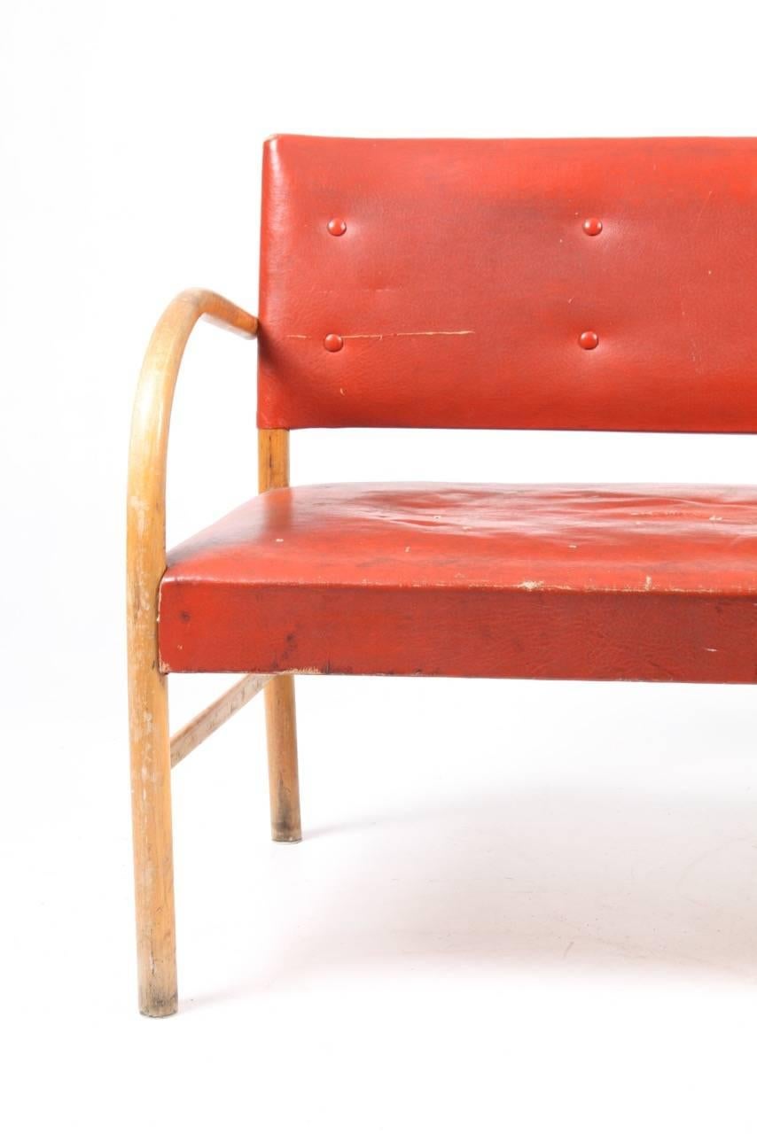 Bench in beech and red vinyl designed by Maa. Frits Schlegel, made by Danish cabinetmaker Fritz Hansen in the 1940s. Fair condition.