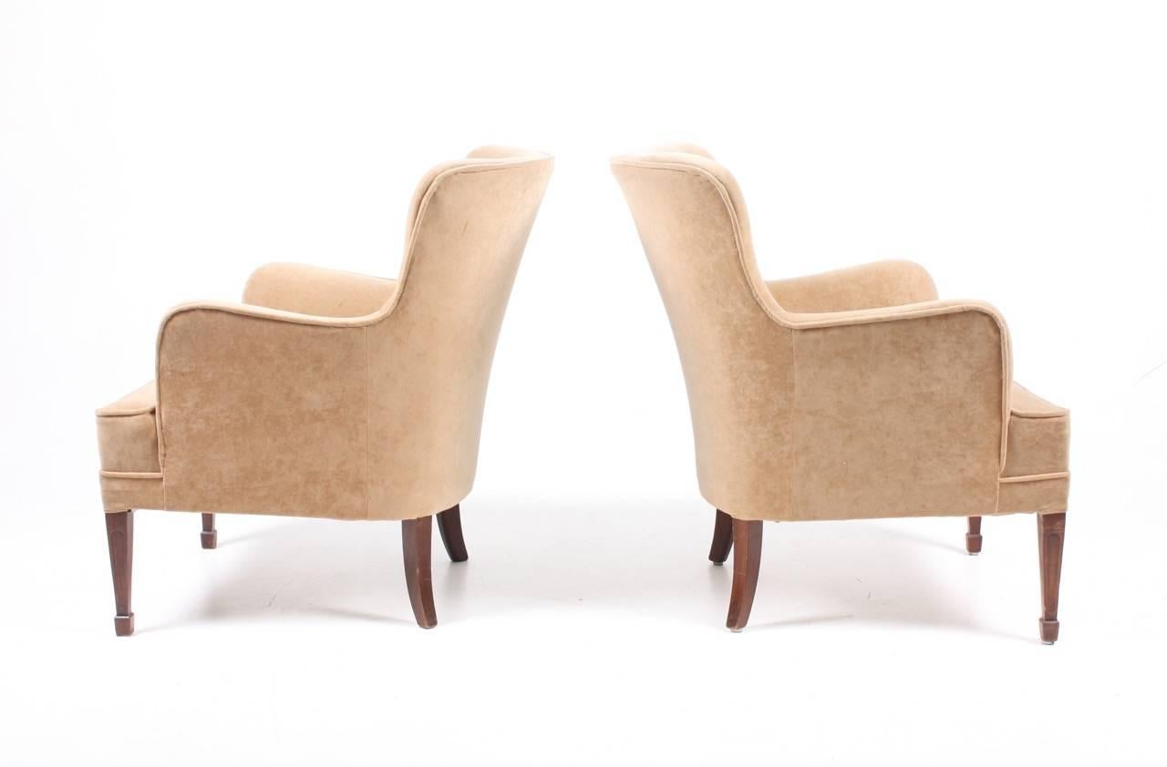 Pair of Classic lounge chairs in velour standing on legs of mahogany. Designed by Maa. Frits Henningsen for Frits Henningesen cabinetmakers .The chairs are made in Denmark in the 1940s and stands in great condition.