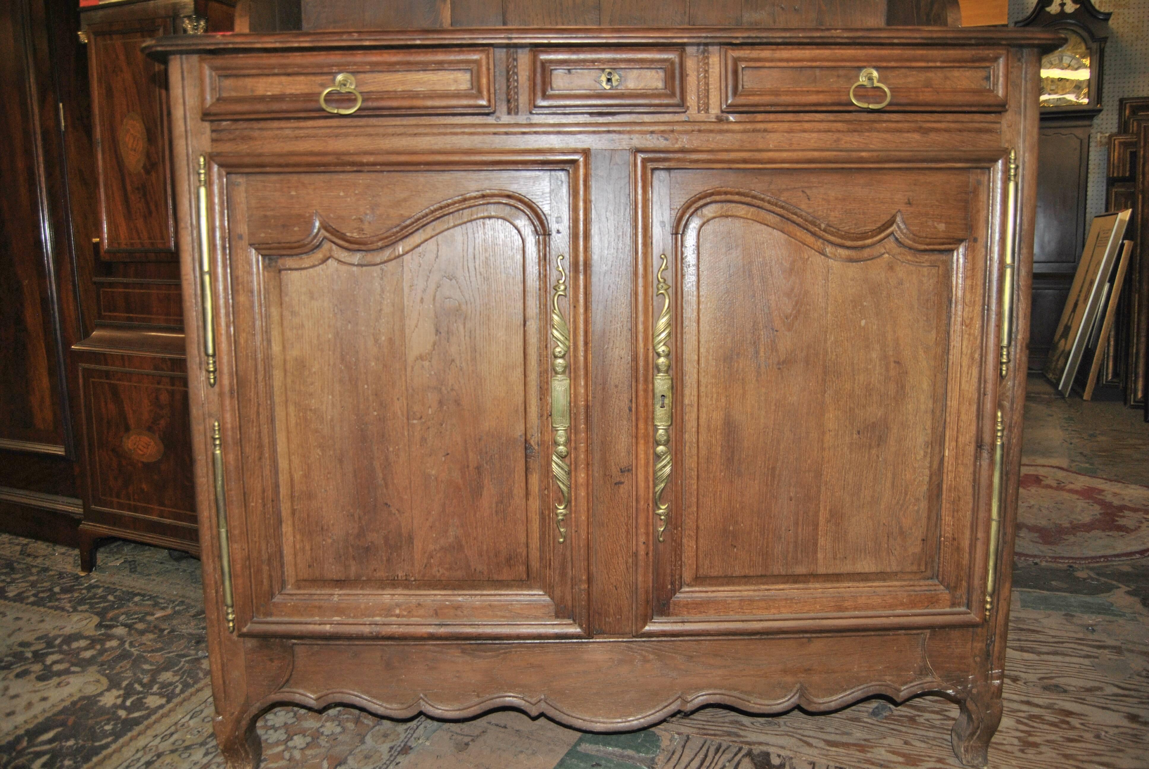 This is an oak country French cupboard, cabinet or plate rack made in France, circa 1850. It has a nicely shaped crown molding to the top. Beneath this there is a pair of shaped doors with brass panels. The panels have heraldic lions on either side