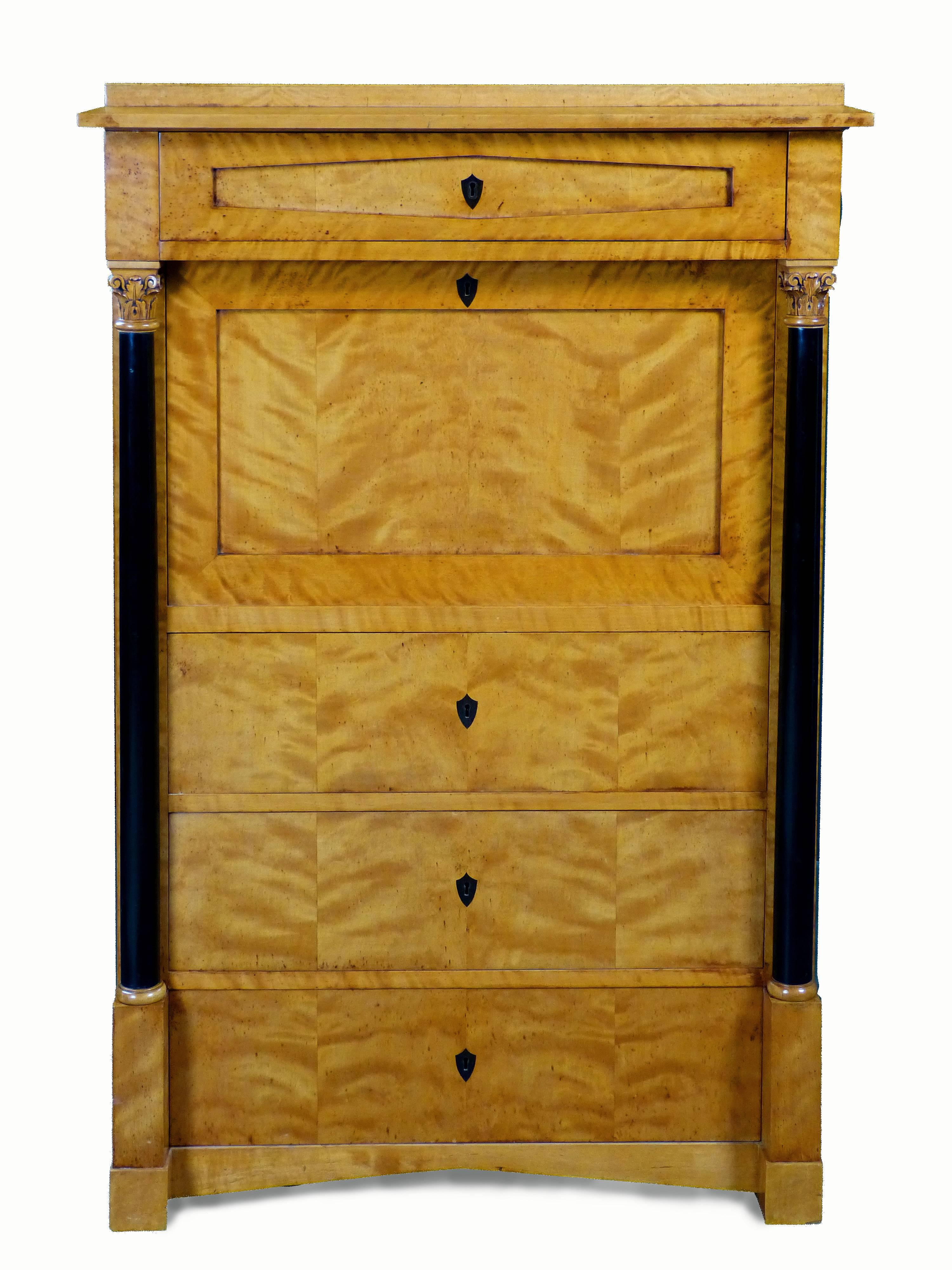 Exquisite Biedermeier secretaire on small dimensions and of Swedish origin, with exterior of satin birch, having ebonized frontal columns with carved tops and 4 large drawers with keys and buffalo Horn shield shaped escutcheons/key holes. The