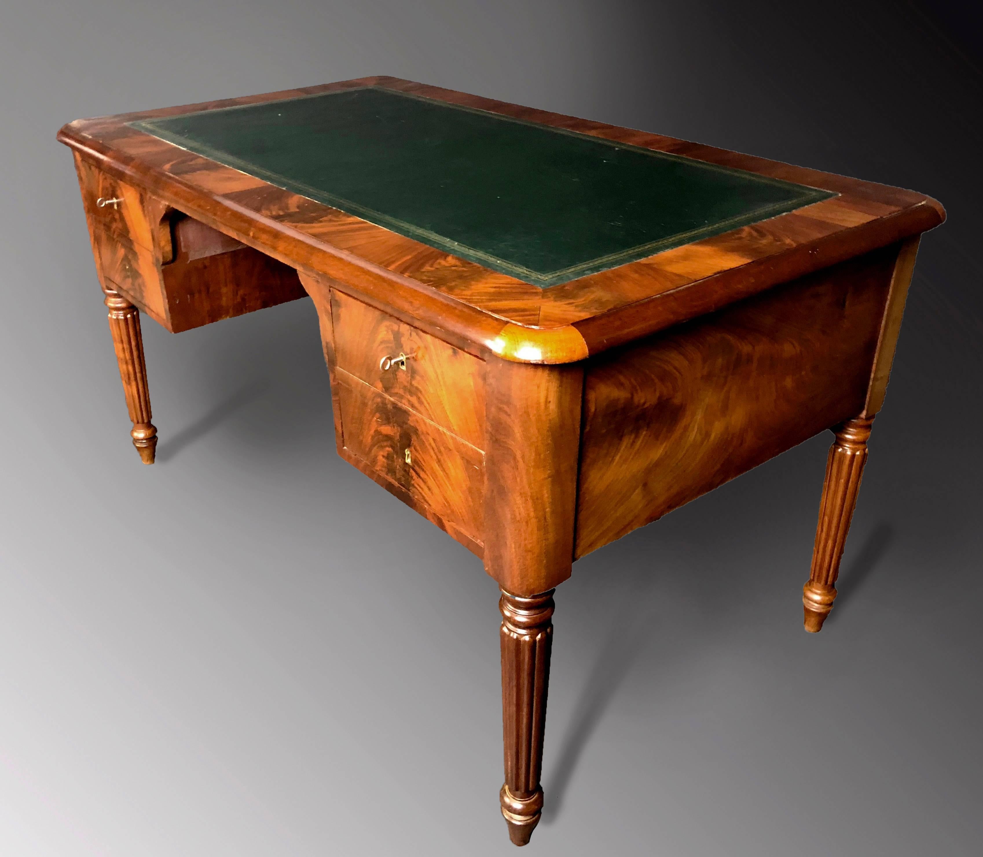 Fine antique writing desk dating to the middle of the 19th century, of the period and style Louis Philippe of France, of outstandingly figured mahogany veneers and with gold tooled green leather writing surface. Four finely turned and profoundly