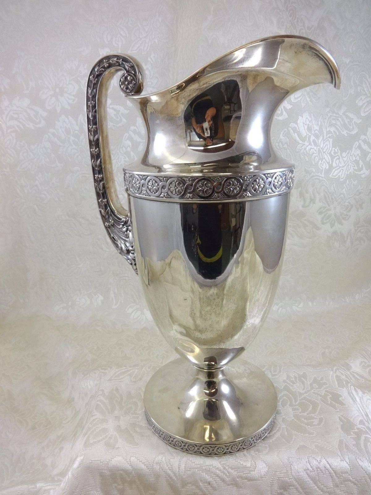 Gorham.

Exceptional Gorham Grecian style monumental sterling silver water pitcher 15" tall x 9" wide and holds 6 1/2" pints. It bears the sword date mark, circa 1915. Weight - 53 troy ounces. It is monogrammed with a lovely vintage