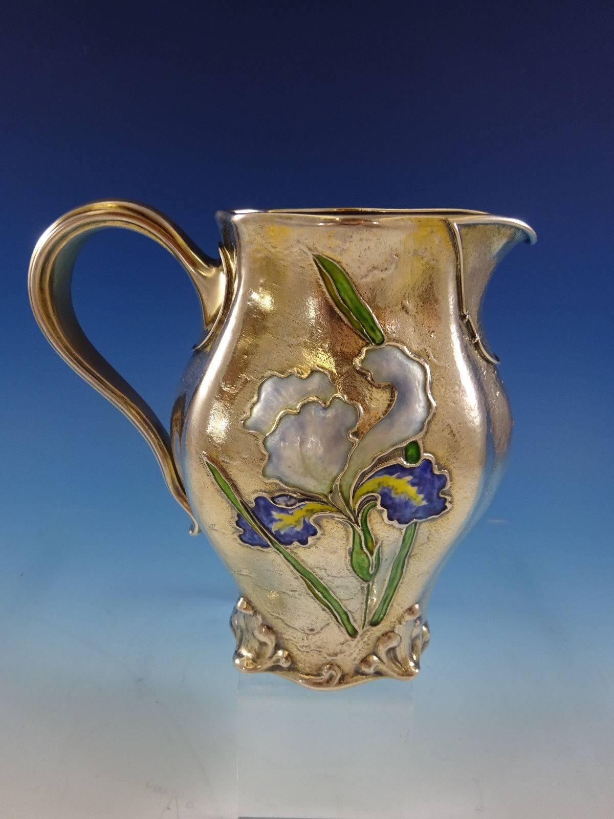 Gorham.
 

Rare sterling silver Vermeil (completely gold-washed) Art Nouveau enameled pitcher made by Gorham with date mark for the year 1897. The front of this fabulous pitcher has a beautifully enameled iris flower. The back of the pitcher has