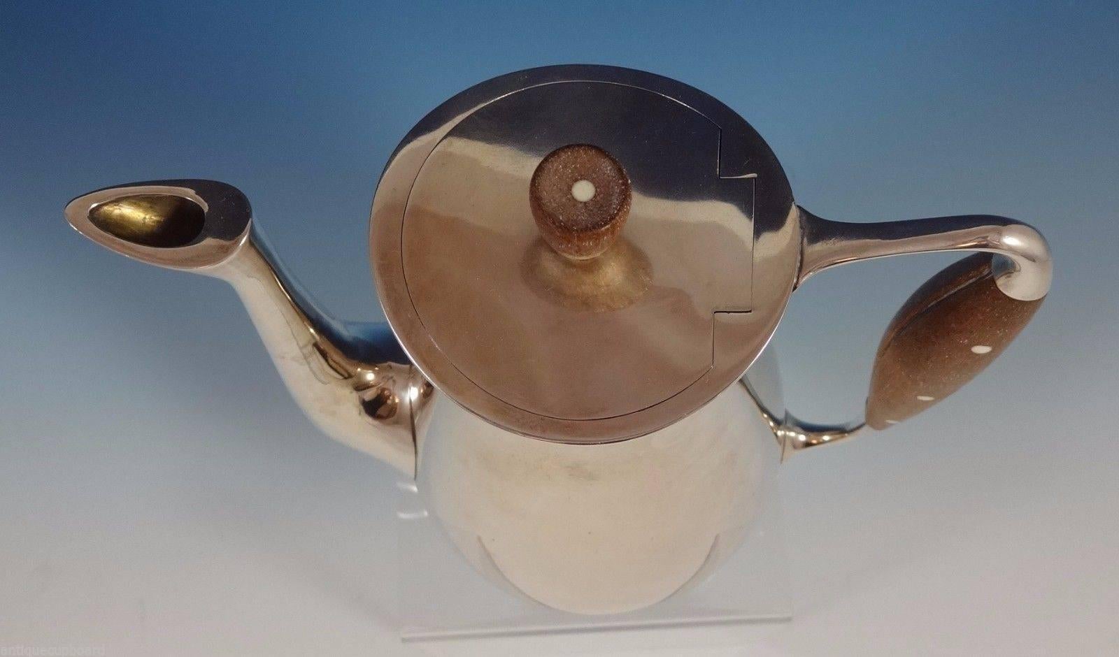 Michelsen.

Modernist Danish sterling silver coffee pot made by Michelson. It has a wood handle and finial inlaid with dots. The piece dates from the 1940-1950s. It measures 8 1/4