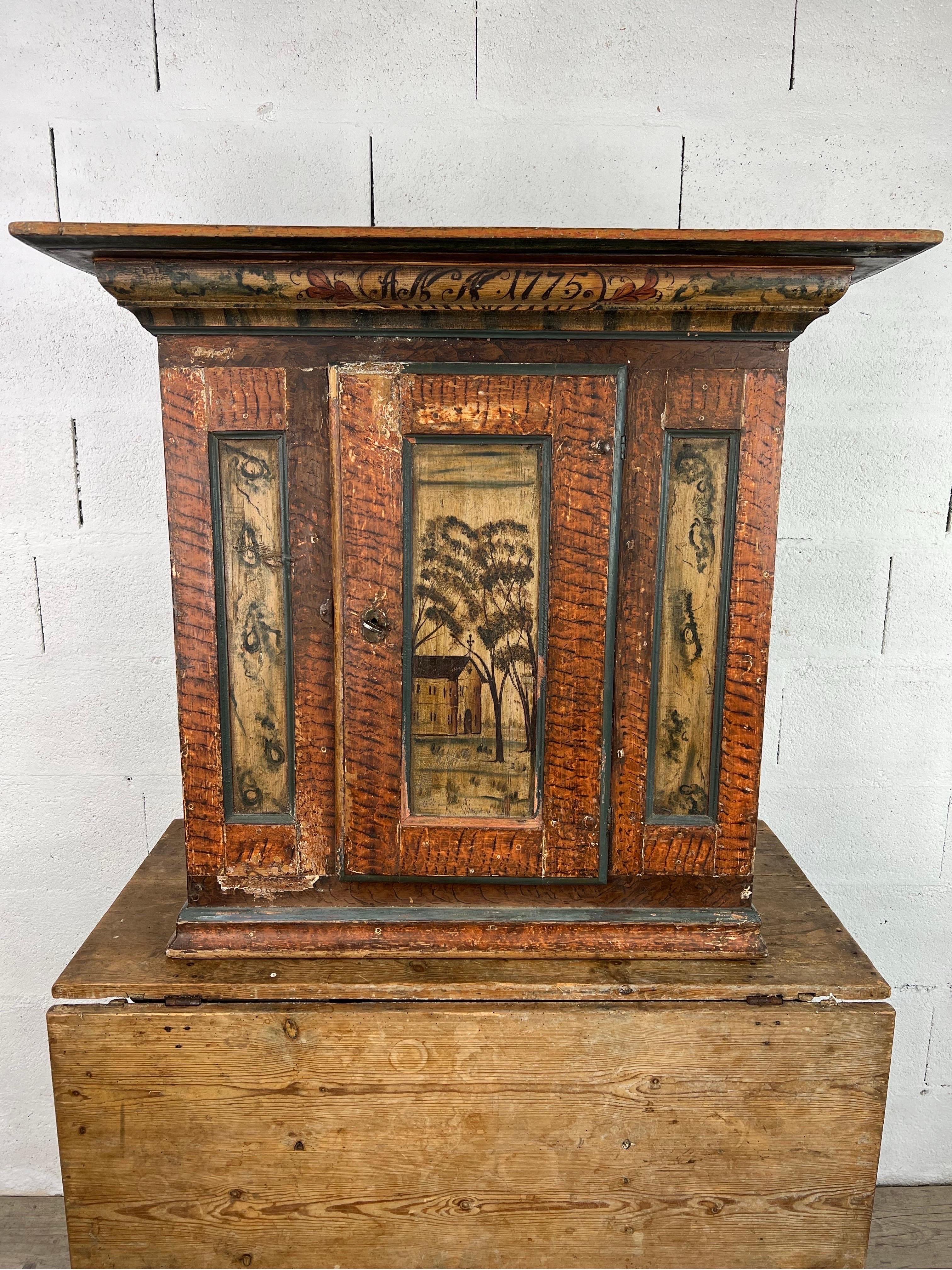 This exceptional Swedish wedding cupboard, dated 1775, is a stunning example of Scandinavian folk art and craftsmanship. Designed to be hung on a wall, it features a meticulously hand-painted faux wood grain, lending warmth and depth to its rustic