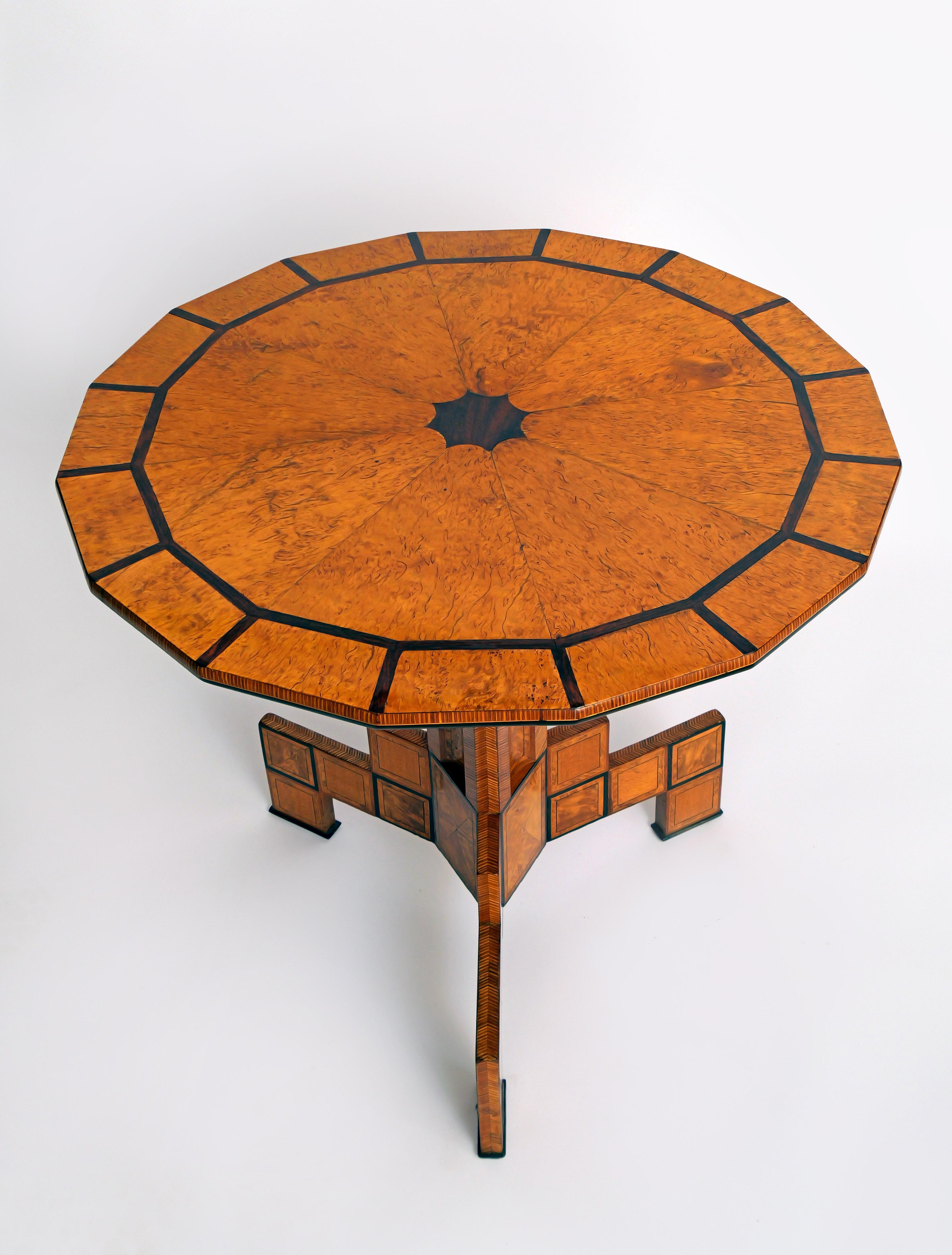 Mesa de té con tablero basculante poligonal y mecanismo de plegado,   
Abedul de Carelia (rizado), fresno, abedul veteado y palisandro 

Países bálticos, hacia 1800  
Altura 70 cm  
111 cm en posición elevada  
Diámetro 75 cm