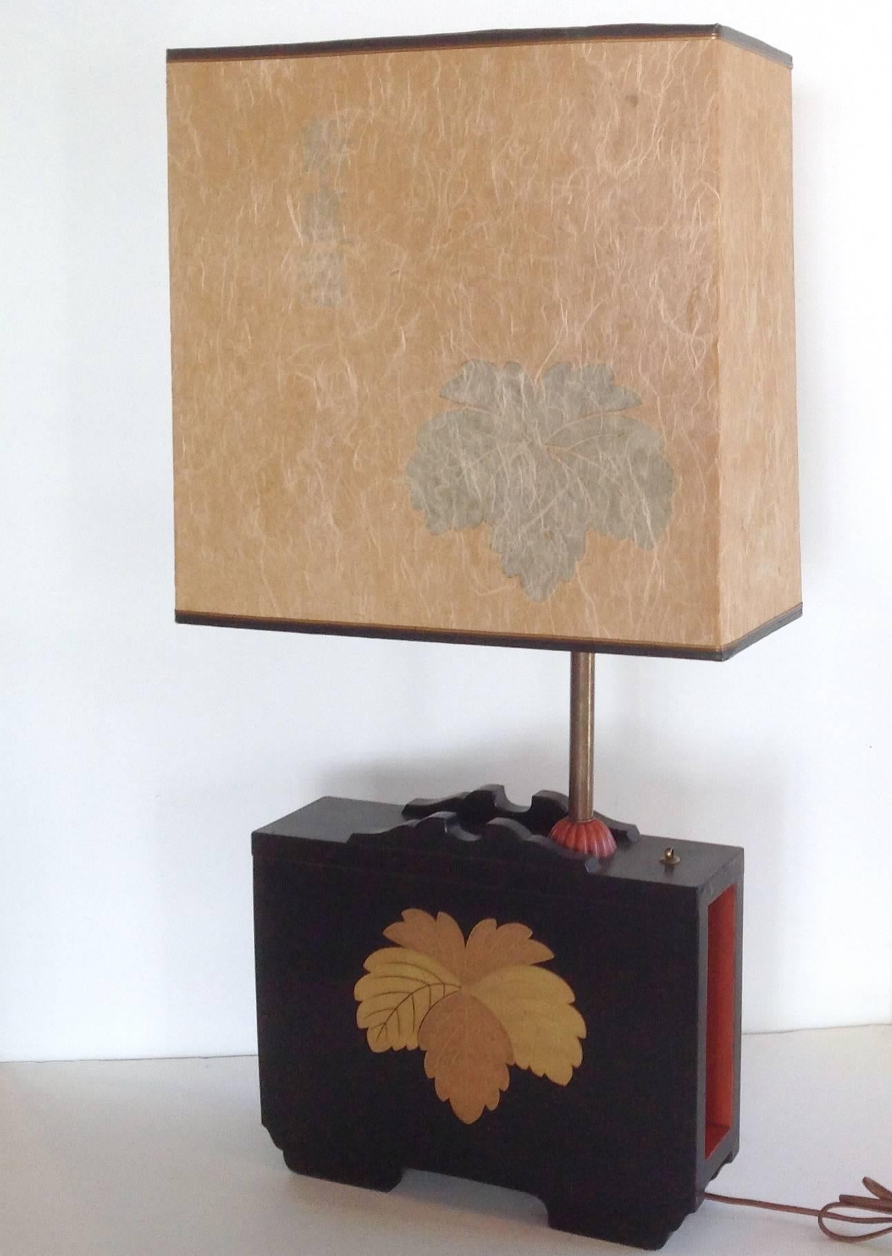 A grand pair of table lamps in the style of Tony Duquette in the Japanese taste. The lamps are comprised of black and red lacquered bases with leaf motif in gold stenciling. Brass rod rising from base with center mogul shade and two addition down