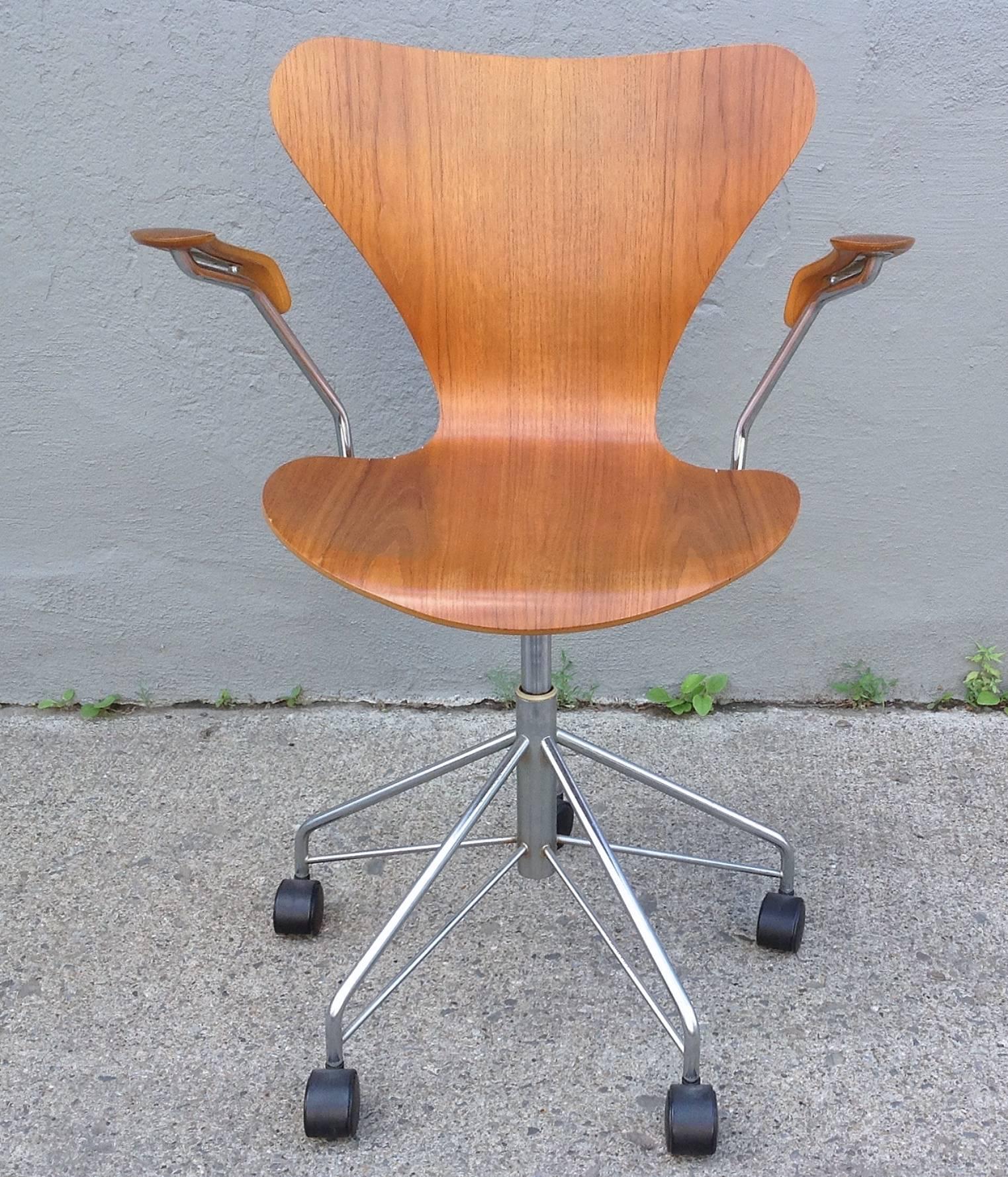 Designed in 1955 by Arne Jacobsen for Fritz Hansen. Rolling desk chair in teak with teak arms produced in 1978. Adjustable seat height, swivel seat, spring back.