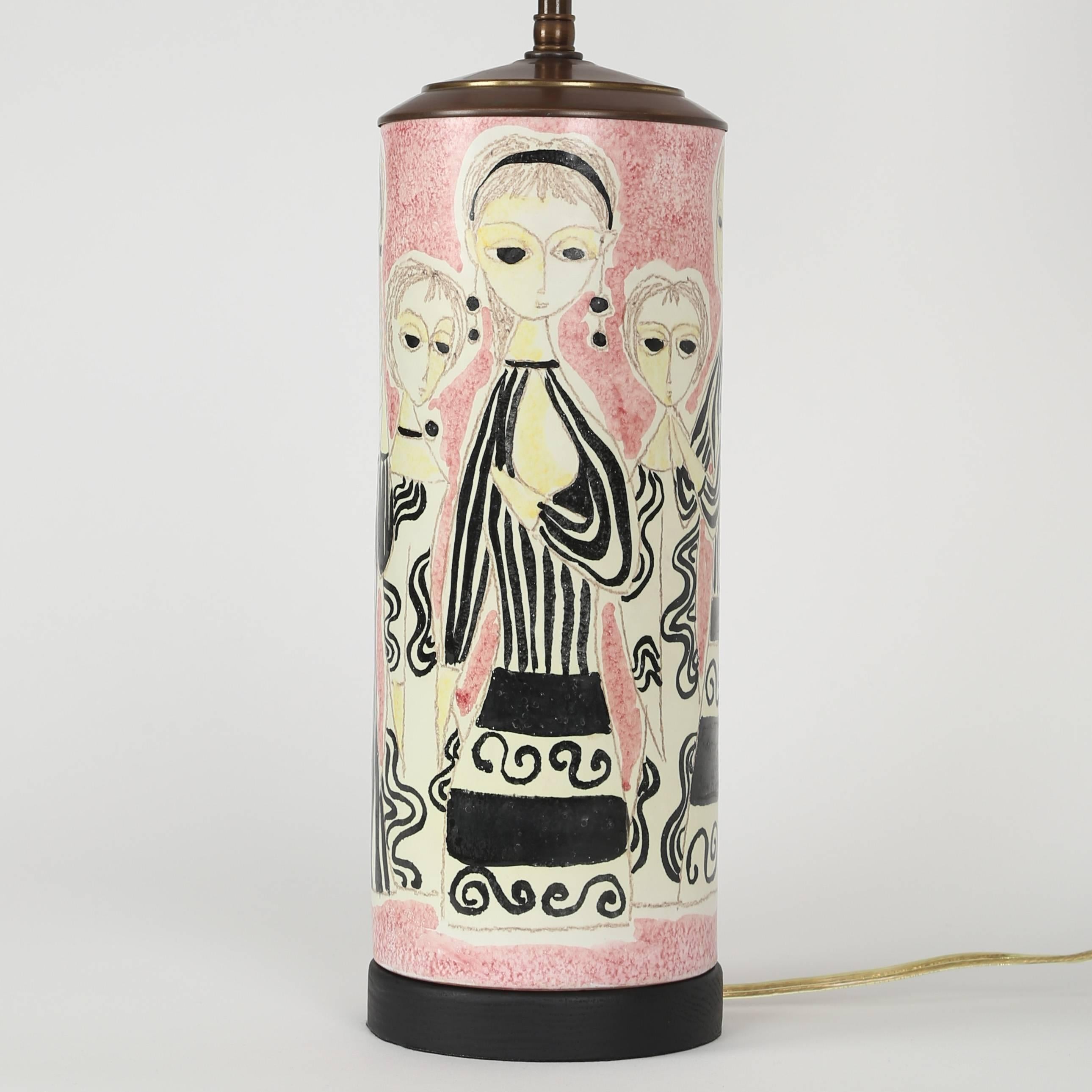 This charming ceramic table lamp features women in mod black-and-white cocktail dresses against a pink background. New antique-brass hardware features double standard-base sockets with pull chains and new wiring. Remains of signature on bottom of