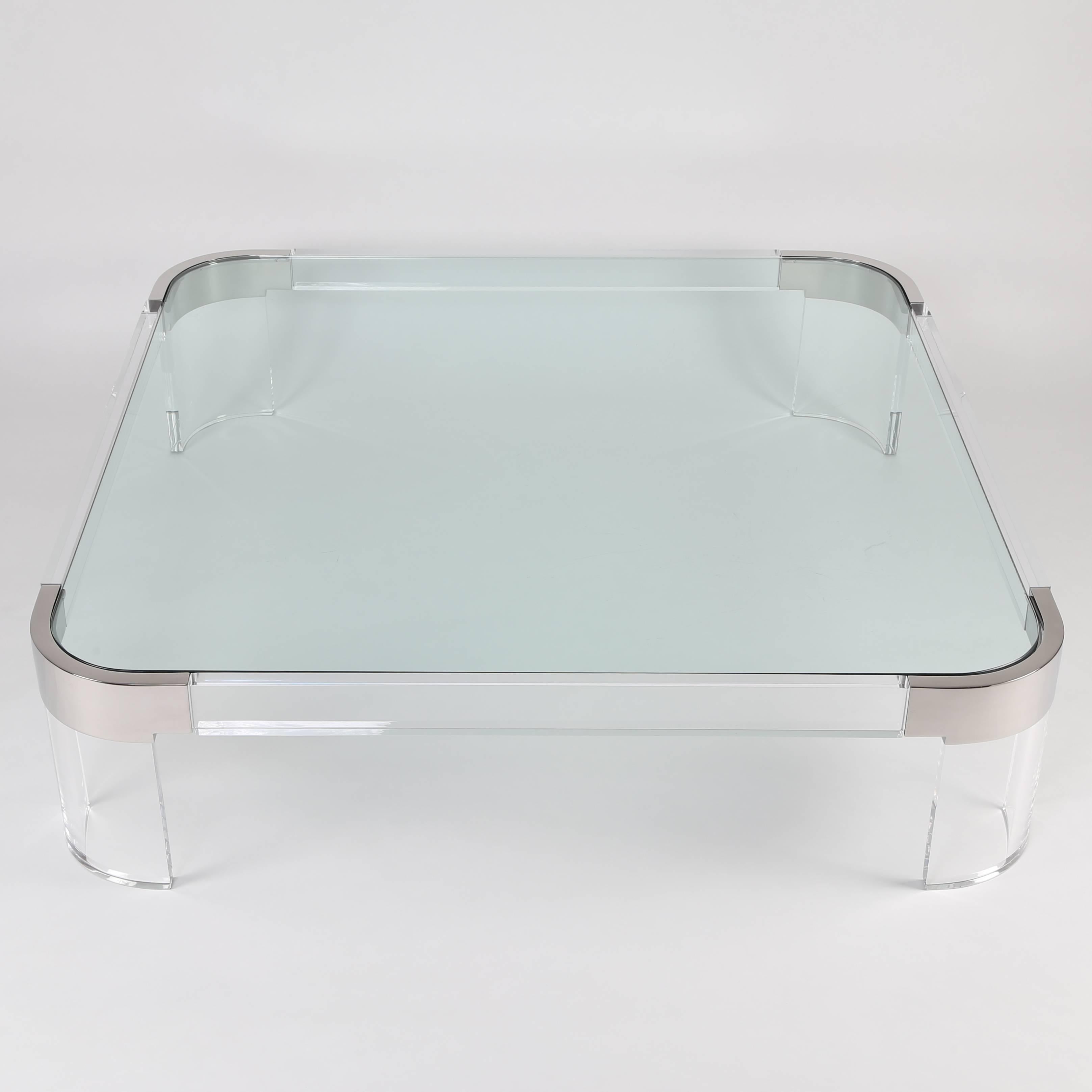 Sleek square coffee table made of thick Lucite, plate glass and polished stainless steel by Charles Hollis Jones. Curved Lucite legs and slab Lucite sides attach with hidden hardware to four stainless-steel corner brackets. An inset 1/2-inch-thick