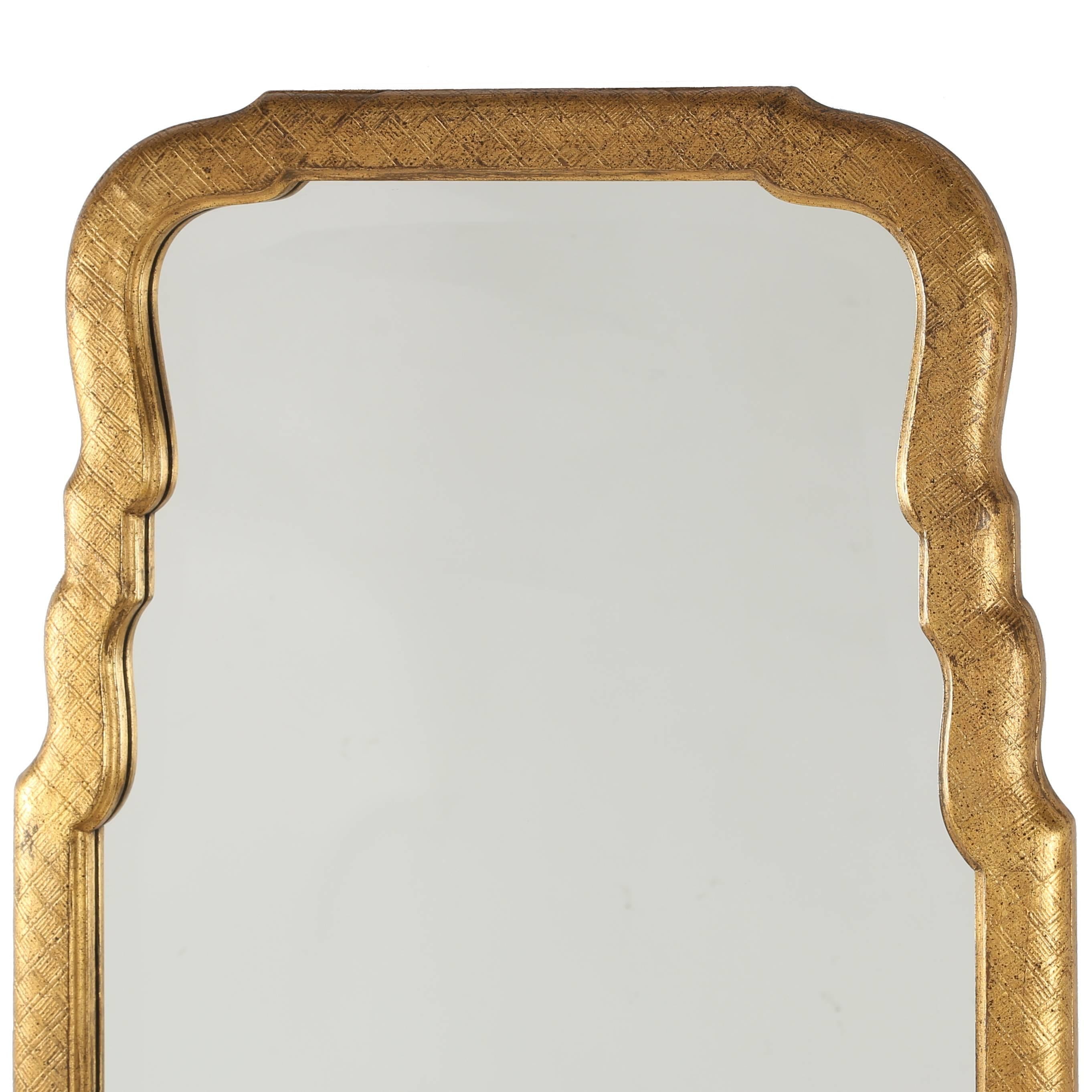 Lovely tall mirror features a subtly carved frame with speckled gilt finish holding the original shapely beveled glass. We have replaced the paper backing and hanging wire but have retained the original 