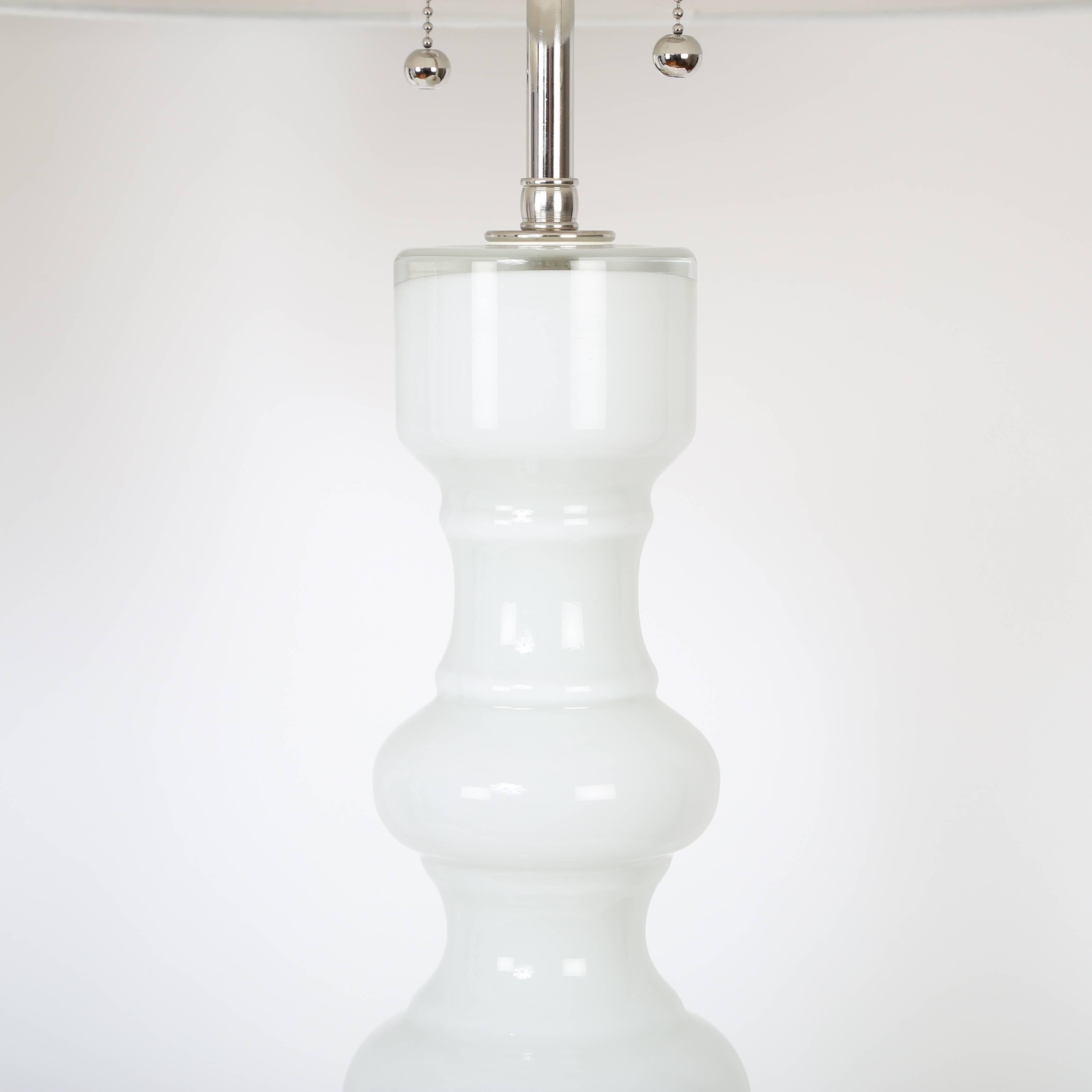 Pair of shapely and tall 1960s white glass table lamps by the Lindshammar glass studio in Sweden. Rewired with new polished-nickel hardware featuring two sockets operated by pull chains. Shades not included. Measures: Overall with shades shown