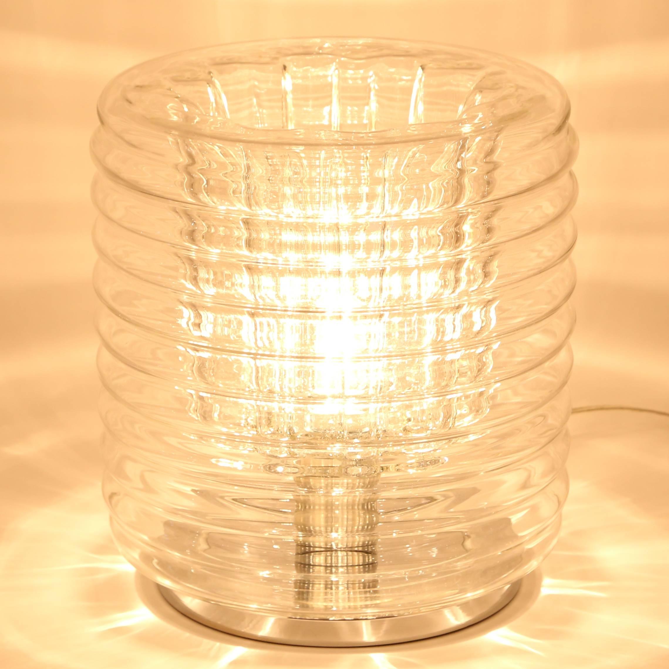 Stylish blown-glass accent lamp with a ribbed exterior and undulating interior. Projects beautiful light patterns in a dimly lit room. Glass globe rests on a weighted chrome base and is held in place by a metal ring that screws onto the porcelain