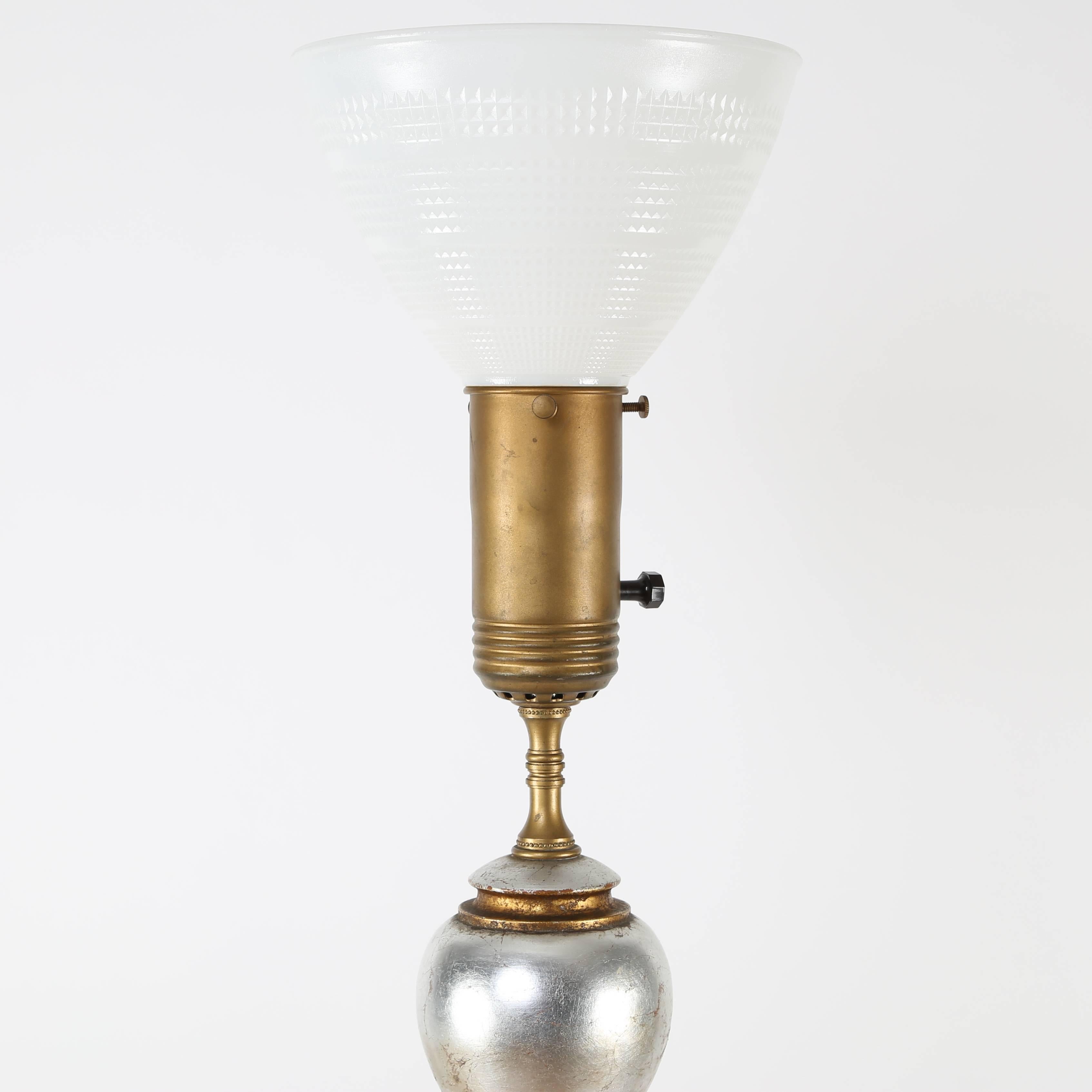 This striking and large table lamp features four stacked and graduated balls finished in gold and silver leaf. Published in 