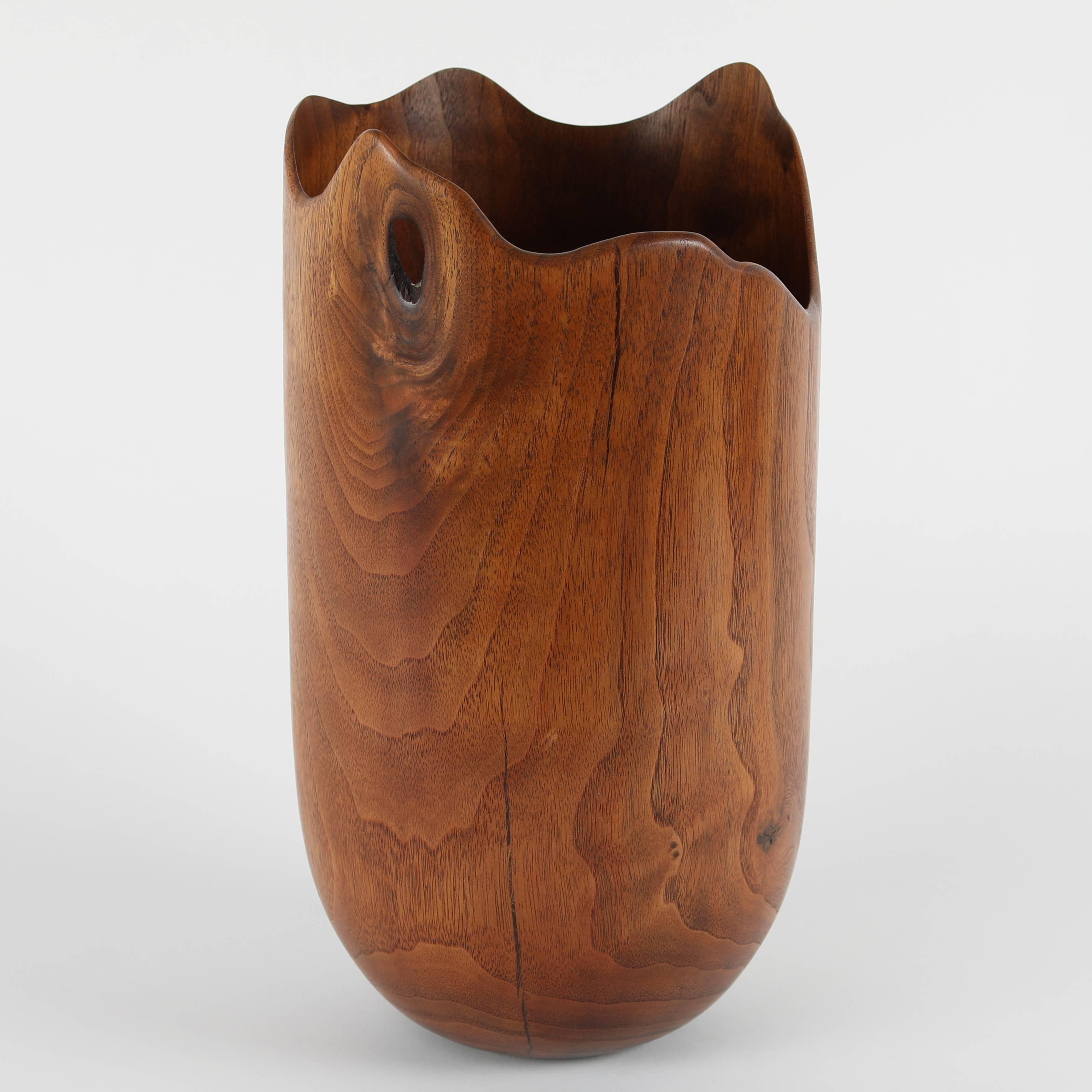 Lovely wood vase carved from American black walnut. The simple form showcases the rich, expressive grain and warm tones of the walnut. Free-form top edge with a hole in the center of a knot. Bottom etched 